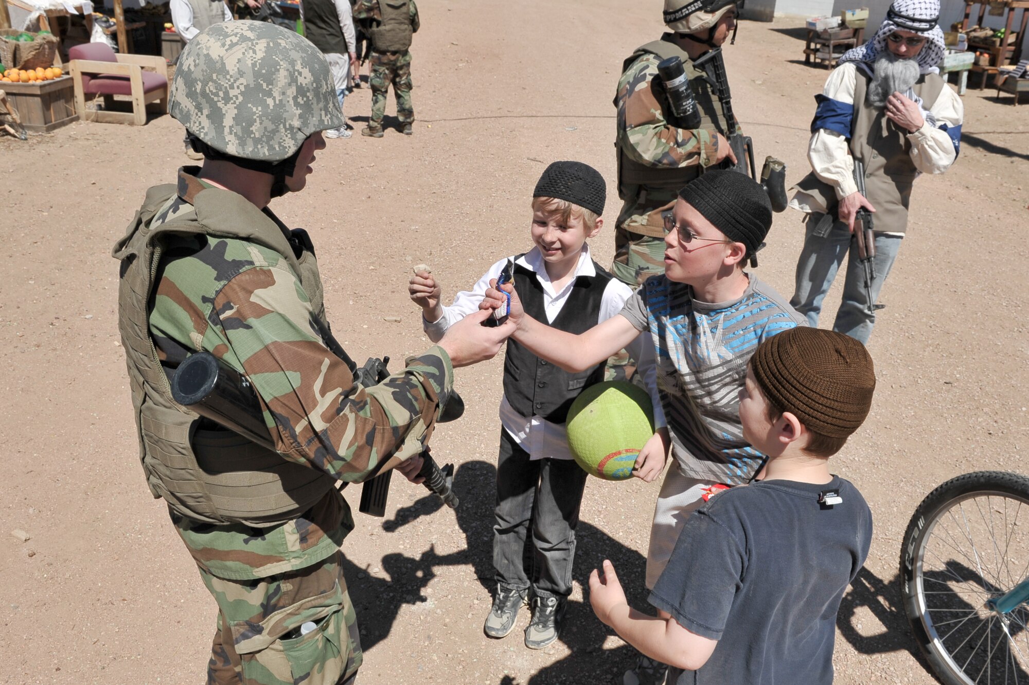 Cadet 1st Class Kaleb Marsh shares candy with children in a mock Afghan village at Fort Carson, Colo., April 2, 2011. Cadet Marsh uses the candy as an opportunity to ask the children about their schooling during a tribal engagement exercise for Behavioral Sciences 460, Sociology of Violence and War. 