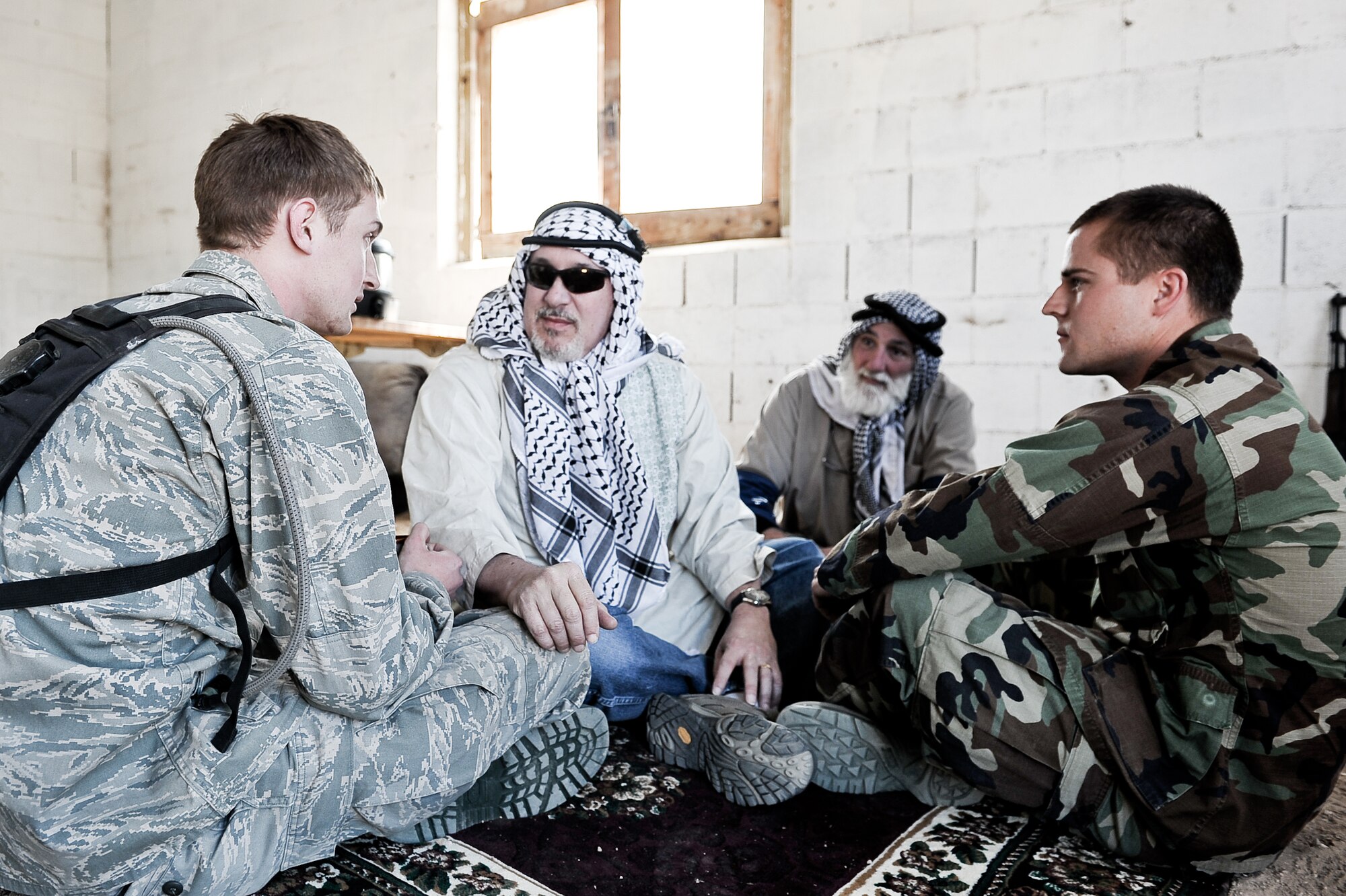 Cadets 1st Class Cody Freeborn, left, and Blake Noble share tea with actors portraying a village elder and chief of police at Fort Carson, April 2, 2011. Cadets from Behavioral Sciences 460, Sociology of Violence and War, travelled to a mock Afghan village to engage the local population for information to meet exercise objectives. (U.S. Air Force Photo/Maj. Jimmy Do)