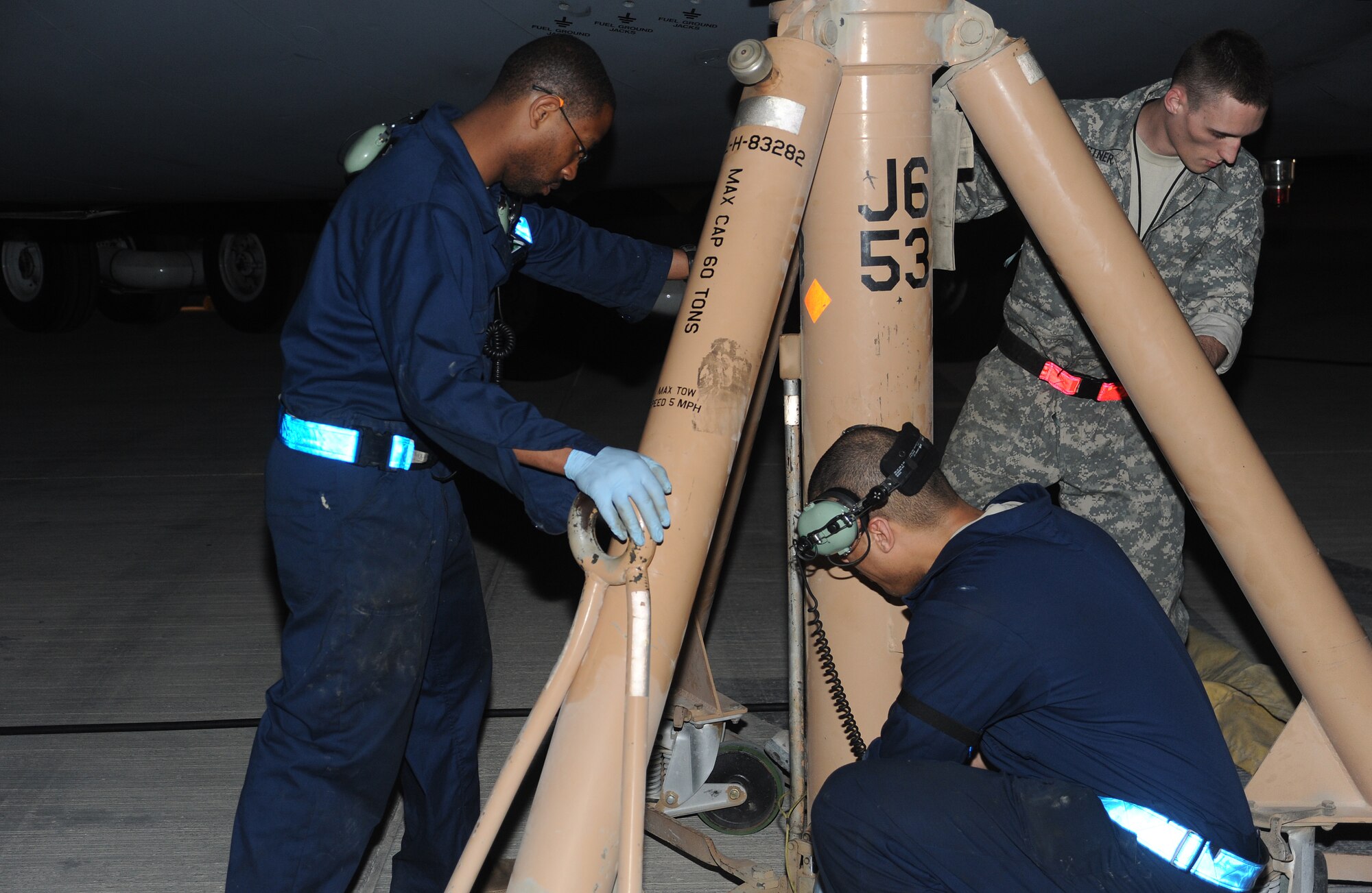 Staff Sergeants Ron Greyson, Shelton Parson and Senior Airman Dan Gerstner, secure a jack stand on a C-5 Galaxy aircraft, on the flightline of an air base in Southwest Asia on April 7.  (U.S. Air Force photo/Staff Sgt. Liliana Moreno)                       