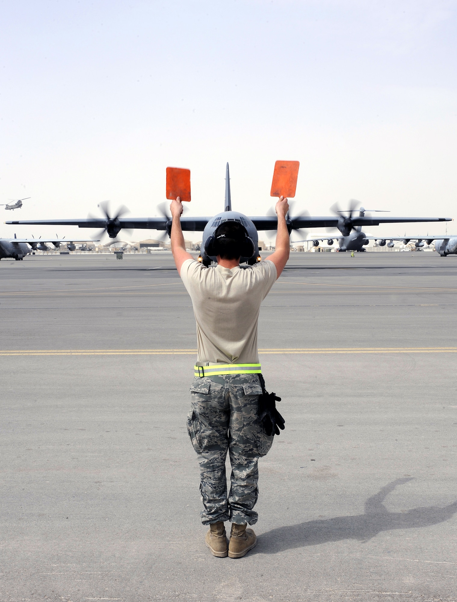 Senior Airman Taylor Noel directs a C-130J Hercules onto a taxiway April 8, 2011, at Kandahar Airfield, Afghanistan. The 772nd Expeditionary Airlift Squadron set a record number of airdrops during the month of March with 72 airdrops of more than 1.5 million pounds of supplies for ground troops across Afghanistan. Airman Noel is a crew chief assigned to the 451st Expeditionary Aircraft Maintenance Squadron. (U.S. Air Force photo/Senior Airman Willard E. Grande II)