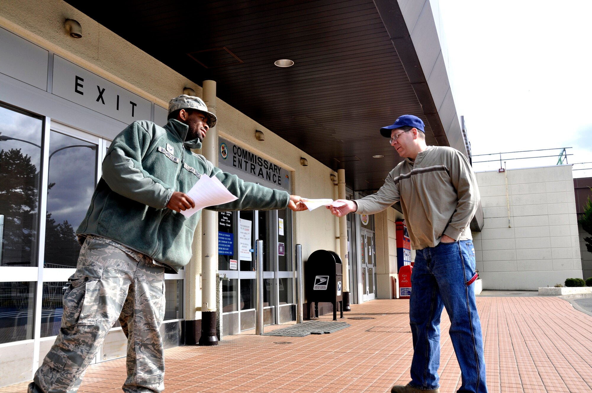 MISAWA AIR BASE, Japan-- Senior Airman Donald Washington, 35th Operations Support Squadron, distributes a flier to Senior Master Sgt. Charles Rettman, 35th Figther Wing Command Center Operations, outside the base commissary here April 8. Airman Washington augmented Misawa Air Base's efforts to remind residents to conserve energy and electricity in the aftermath of the 7.1-magnitude aftershock in Japan April 7. (U.S. Air Force photo by Senior Airman Joe W. McFadden/RELEASED) 