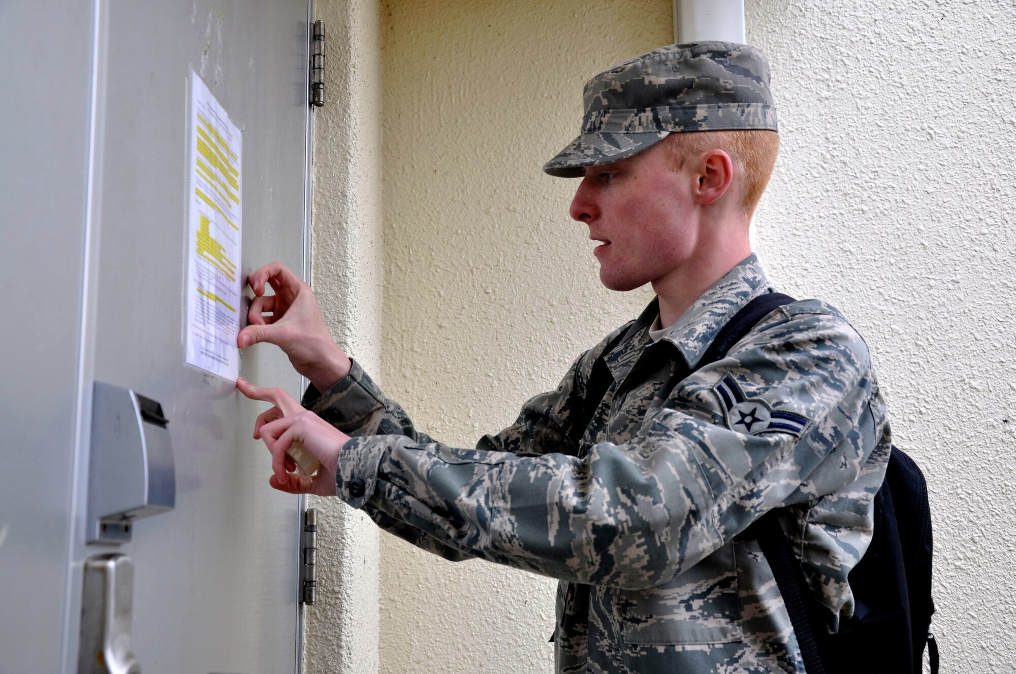MISAWA AIR BASE, Japan--  Airman 1st Class Theodore Nicoloff, 35th Maintenance Operations Squadron maintenance management productions apprentice, posts a notice on the door of one of the base dormitories here April 8. Airman Nicoloff, a native of Greer, S.C., augmented Misawa Air Base's efforts to remind residents to conserve energy and electricity in the aftermath of the 7.1-magnitude aftershock in Japan April 7. (U.S. Air Force photo by Senior Airman Joe W. McFadden/RELEASED)