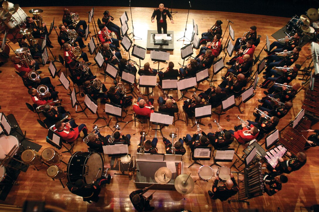 Members of The President’s Own United States Marine Band sit among the Marines of the III Marine Expeditionary Force Band and contribute their talent as they perform various patriotic songs during “Coats of Red and Blue” at the theater on Camp Foster April 8.