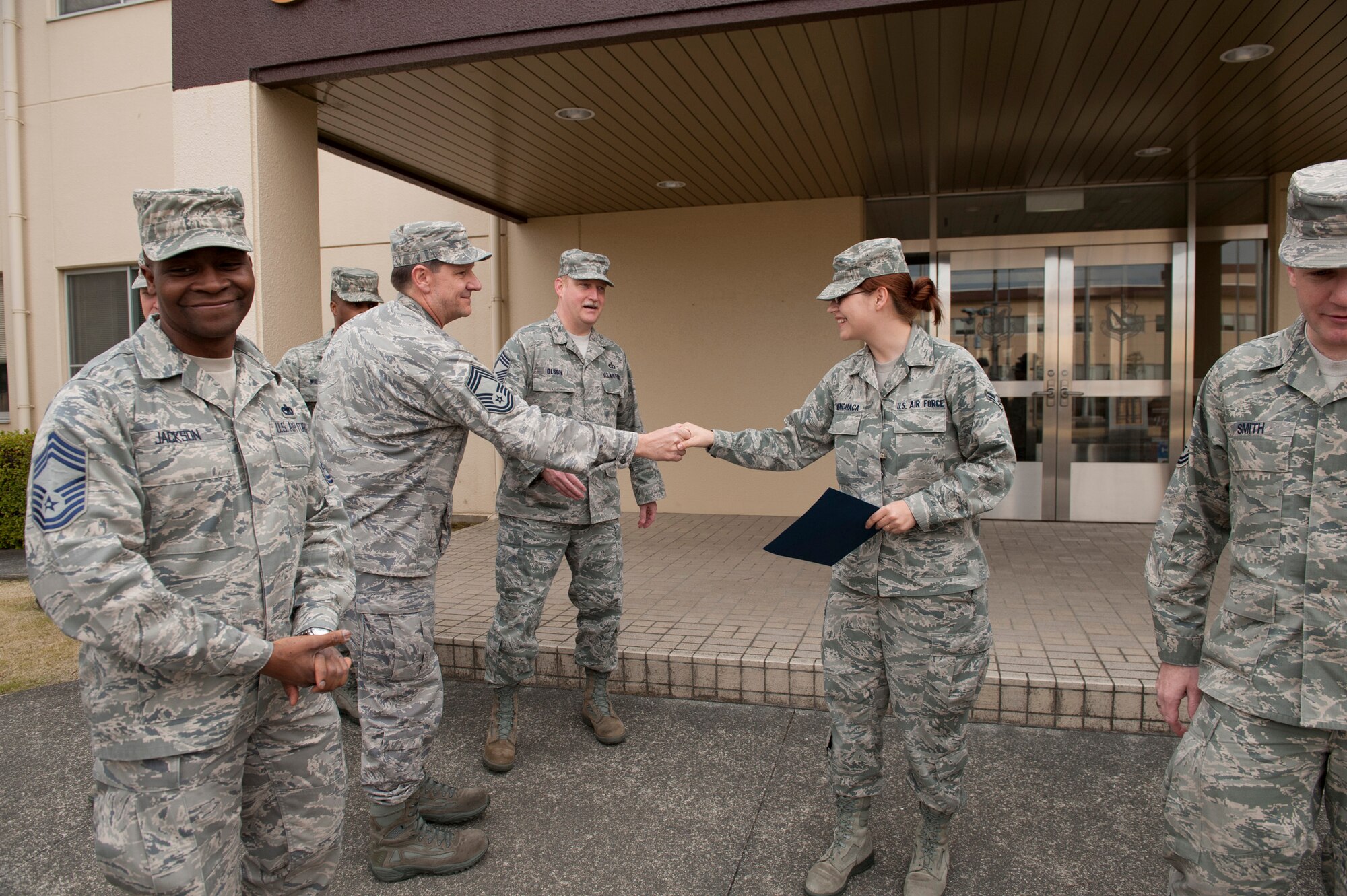 YOKOTA AIR BASE, Japan -- Members of the Yokota Chiefs' Group congratulate Airman 1st Class Katrina Menchaca outside the 374th Airlift Wing headquarters, Yokota Air Base, Japan, April 7, 2011. Airman Menchaca, a journalist with the wing public affairs office, received the Yokota Chiefs' Group "sharp troop" award. (U.S. Air Force photo/Staff Sgt. Samuel Morse)