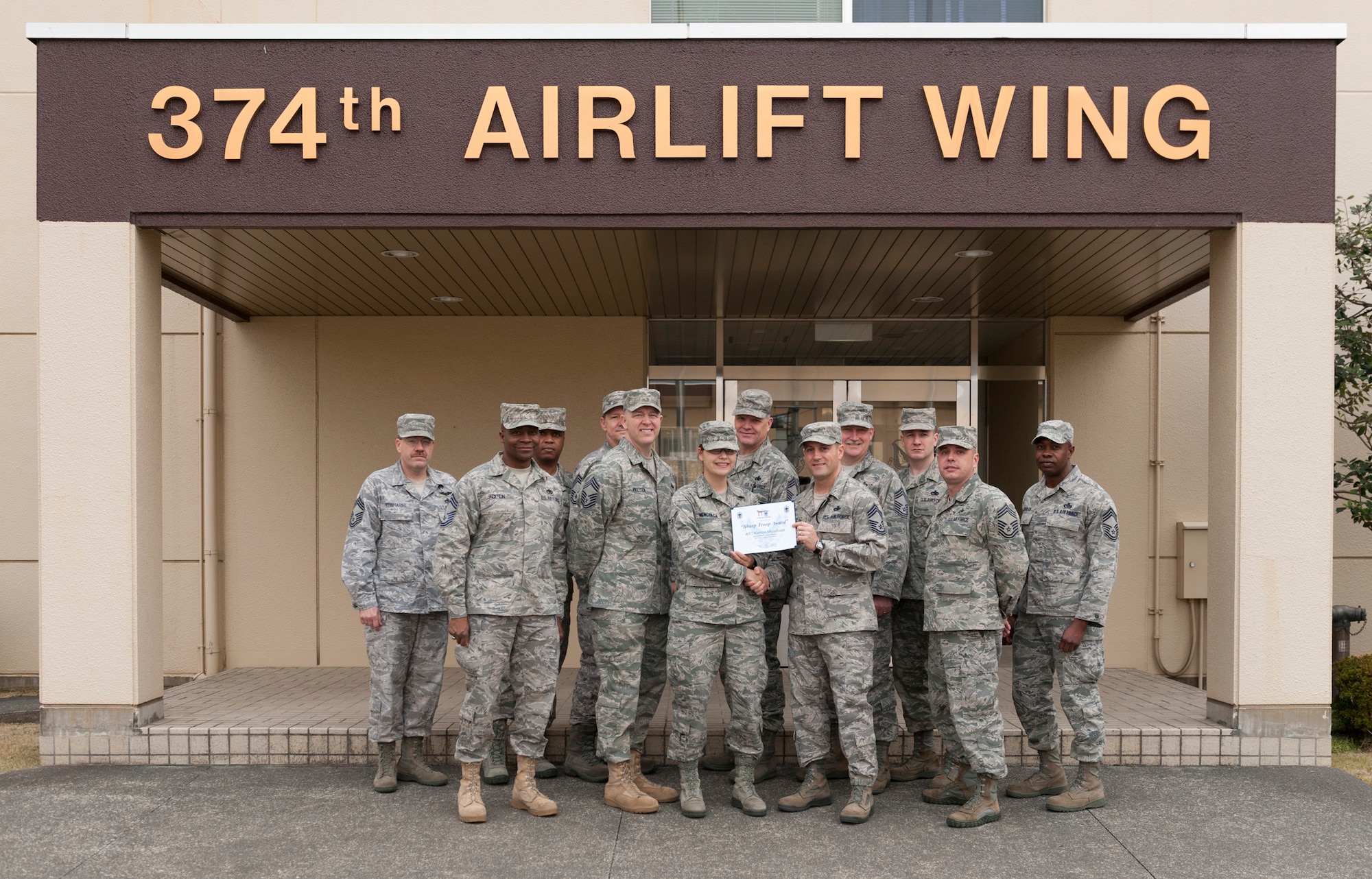 YOKOTA AIR BASE, Japan -- Airman 1st Class Katrina Menchaca, 374th Airlift Wing Public Affairs journalist, poses for a photo with the Yokota Chiefs' Group at the wing headquarters, Yokota Air Base, Japan, April 7, 2011. The chiefs' group presented Airman Menchaca with their "sharp troop" award. (U.S. Air Force photo/Staff Sgt. Samuel Morse)