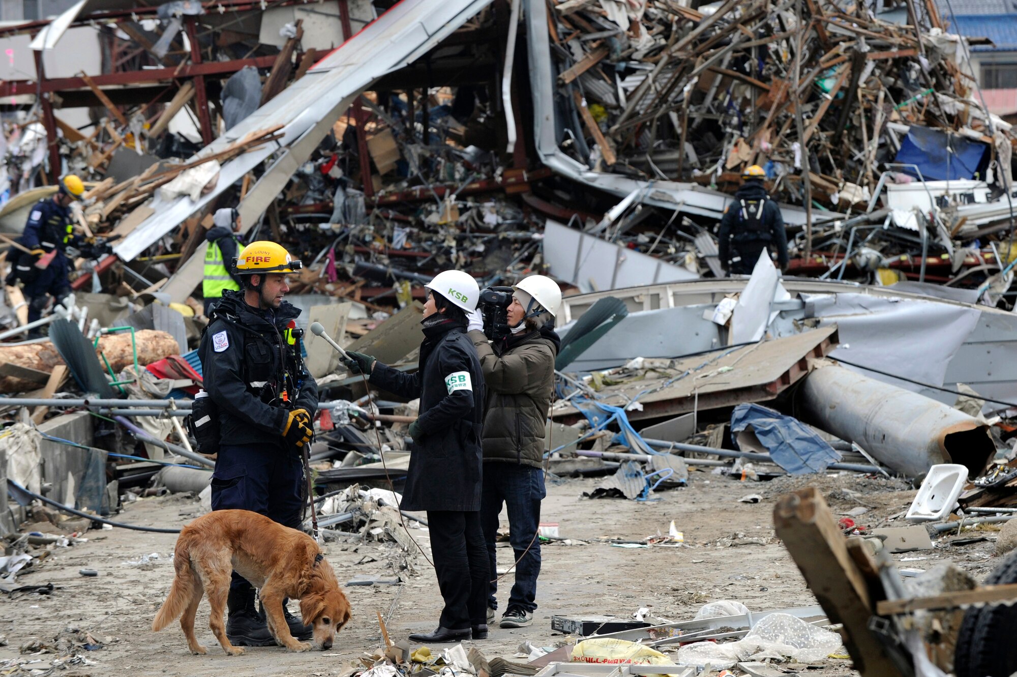 A K-9 handling firefighter for CA-TF2 is interviewed by Japanese media  while on a search for tsunami victims in Ofunato, Japan on March 15, 2011. The Los Angeles County Fire Urban Search and Rescue Team, Task Force 2, travelled with the 452nd Air Mobility Wing, March Air Reserve Base, Calif., to the earthquake and tsunami stricken areas of Japan just four days after the devastation.  (U.S. Air Force photo/Technical Sgt. Daniel St. Pierre)