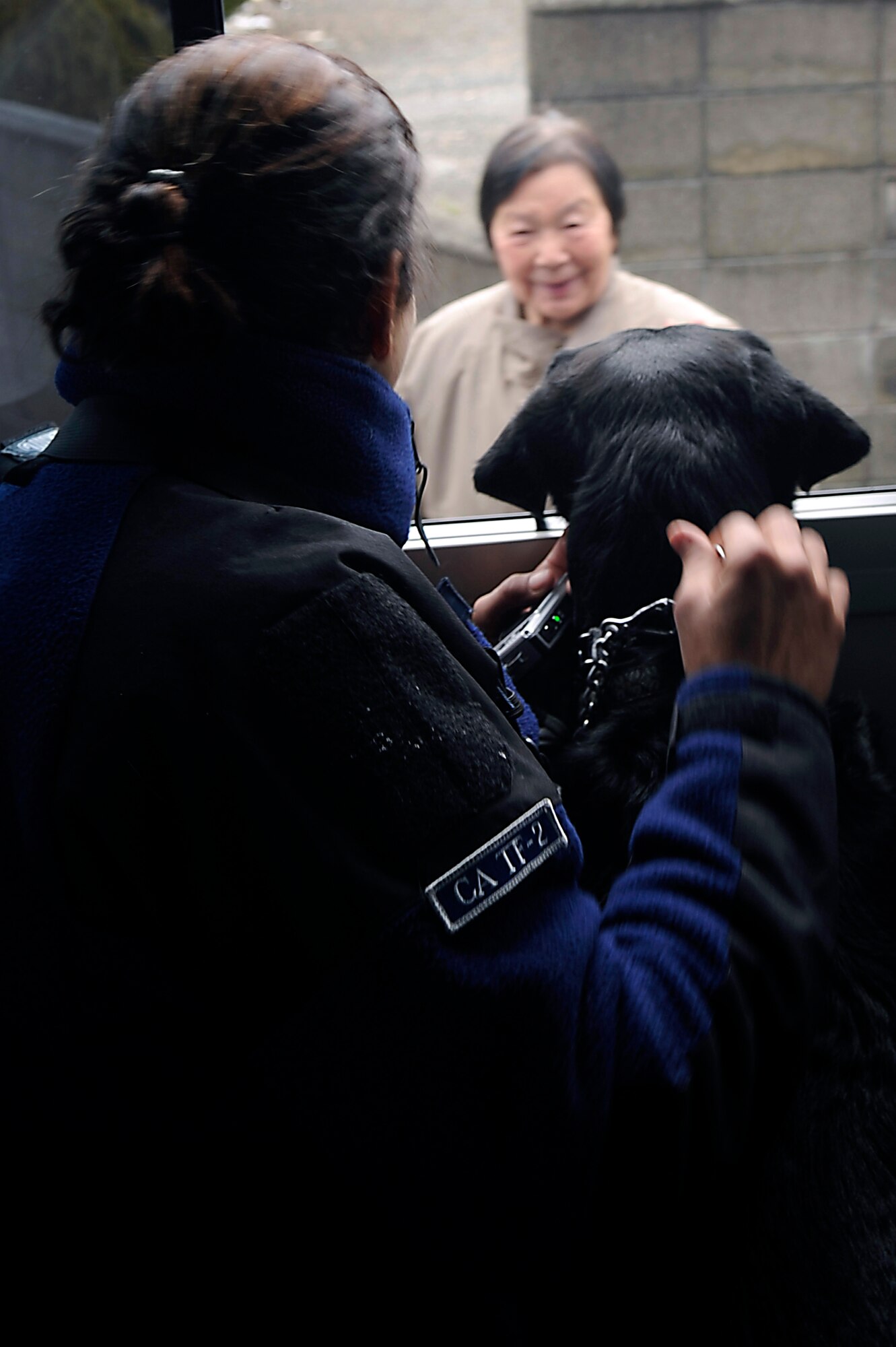 A Japanese woman smiles as Jasmine Segura, a dog handler and her dog, Cadillac  pass by enroute to their search and recovery site on March 15, 2011.  The Los Angeles County Fire Urban Search and Rescue Team, Task Force 2, travelled with the 452nd Air Mobility Wing, March Air Reserve Base, Calif., to the earthquake and tsunami stricken areas of Japan just four days after the devastation.  (U.S. Air Force photo/Technical Sgt. Daniel St. Pierre)