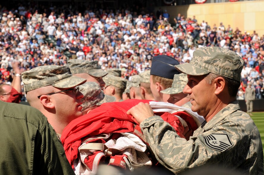 Members of the Minesota Air National Guard and Minnesota Army National Guard unravel a 1600 pound flag held by over 130 Soldiers and Airmen during the Minnesota Twins home opener April 8, 2011 at Target Field in Minneapolis. USAF official photo by Tech. Sgt. Erik Gudmundson