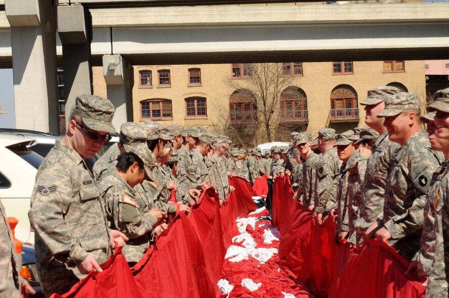 Members of the Minesota Air National Guard and Minnesota Army National Guard unravel a 1600 pound flag held by over 130 Soldiers and Airmen during the Minnesota Twins home opener April 8, 2011 at Target Field in Minneapolis. USAF official photo by Tech. Sgt. Erik Gudmundson