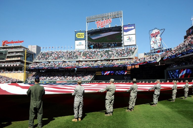 Members of the Minesota Air National Guard and Minnesota Army National Guard unravel a 1600 pound flag held by over 130 Soldiers and Airmen during the Minnesota Twins home opener April 8, 2011 at Target Field in Minneapolis. USAF official photo by Tech. Sgt. Erik Gudmundson