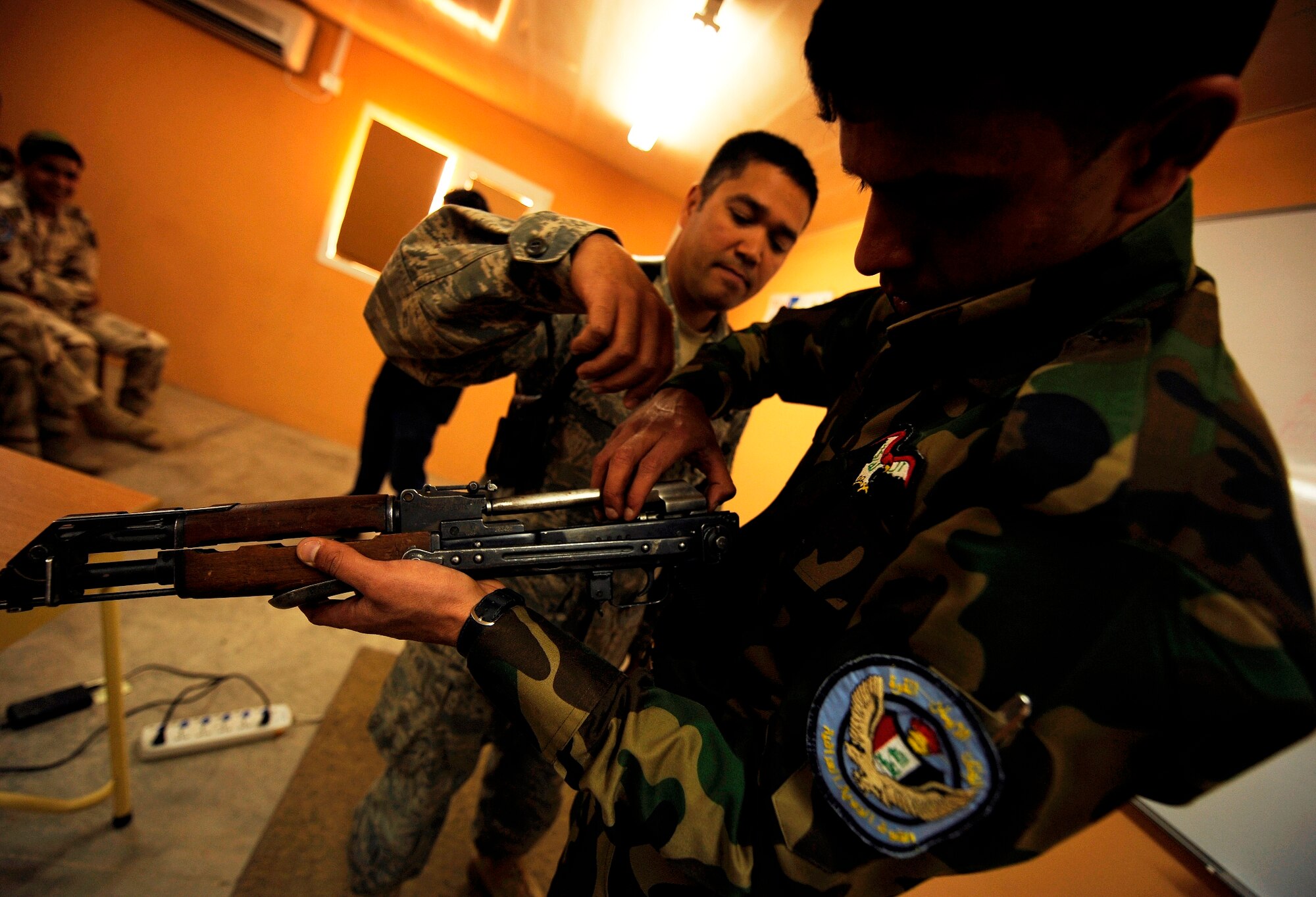 KIRKUK REGIONAL AIR BASE, Iraq -- Tech. Sgt. Daniel Delossantos, 407th Expeditionary Security Forces Squadron, helps an Iraqi airman reassemble an AK-47 rifle during a two-week training course April 5.  Sergeant Delossantos is deployed from Davis-Monthan Air Force Base, Ariz. (U.S. Air Force/Tech. Sgt. Jason Lake)