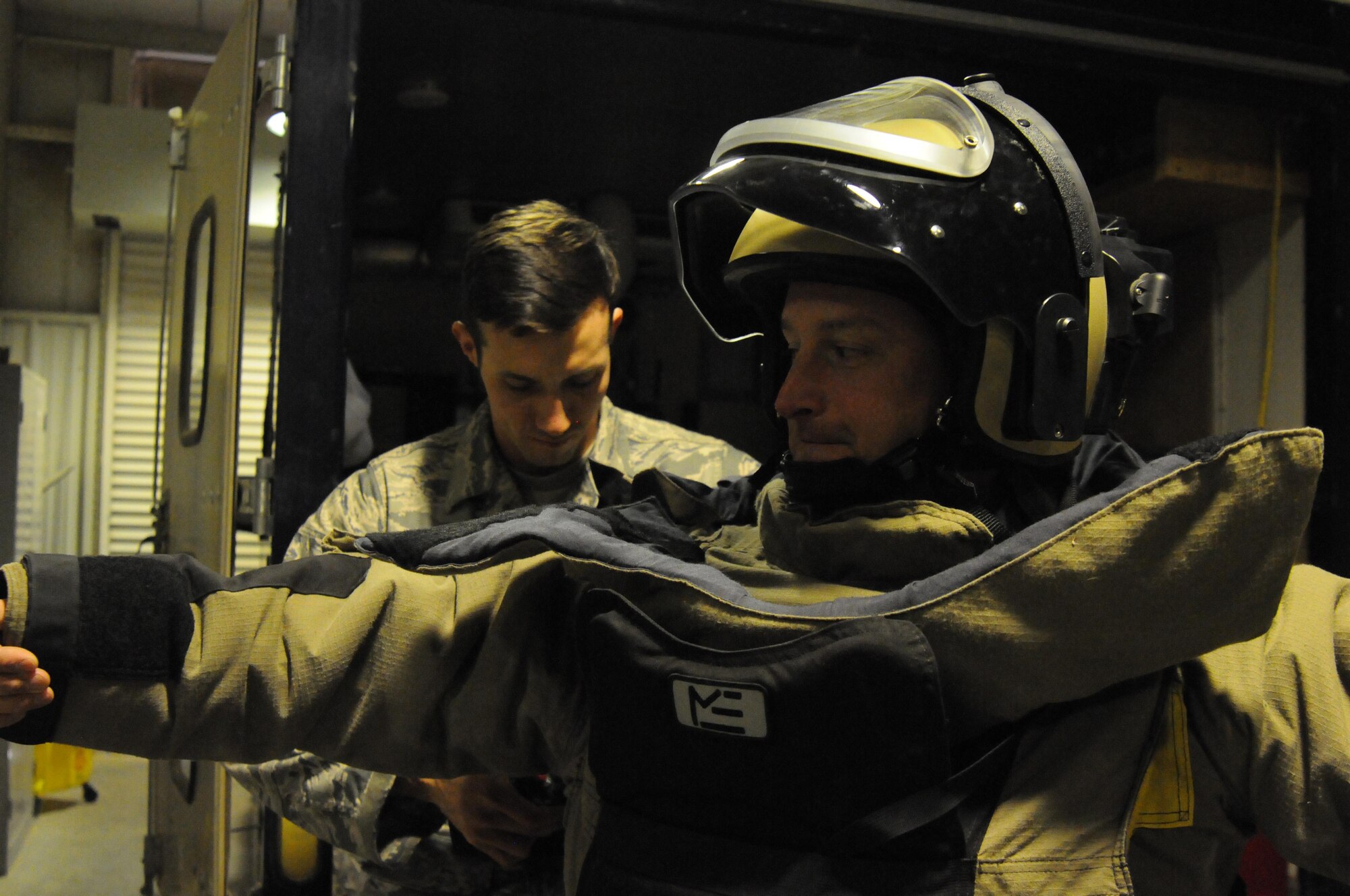 Staff Sgt. Aaron Flanagan, an explosive ordnance disposal technician with the 386th Expeditionary Civil Engineer Squadron, adjusts the back of the bomb suit worn by Staff Sgt. Benjamin Cully, a firefighter also with the 386th ECES. Sergeant Cully participated in the Rock Top III's Shadow Program, which allows enlisted members to shadow senior noncomissioned officers in another careerfield. (U.S. Air Force photo by Staff Sgt. Patrice Clarke)
