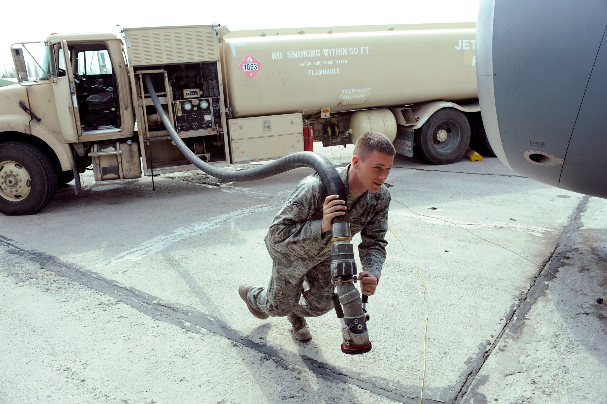 TRANSIT CENTER AT MANAS, Kyrgyzstan - Airman 1st Class Tanner Dalton, 376th Expeditionary Logistics Readiness Squadron petroleum, oil and lubricants specialist, drags a fuel line to a KC-135 "Stratotanker" here April 1.  Airman Dalton, deployed from the 27th Special Operations Logistics Readiness Squadron at Cannon AFB, N.M., helped achieve the squadron  record, of pumping 587,546 gallons of jet fuel in a 24-hour period back on March 11.  Previously, the 51-person and four Kyrgyz personnel-held record was set February 18 at 544,758 gallons in 24 hours.  (U.S. Air Force photo/Tech. Sgt. Jerome C. Baysmore) 