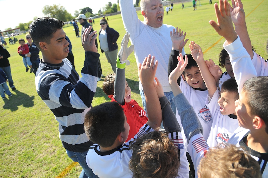 Sgt. Rodolfo Ayala, Yuma Dragons soccer coach, left, celebrates with his team after a victory at Rancho Viejo Elementary School in Yuma, Ariz., April 9, 2011. The team, which is comprised of both local children and those of Marines, has a record of 5-1 so far in its season, leading their league in total number of goals scored.