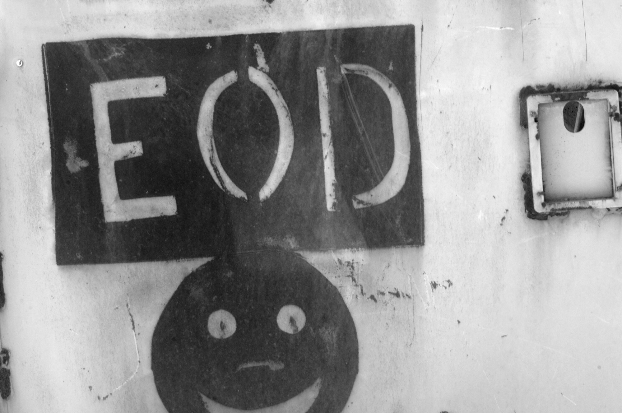 An explosive ordnance disposal logo is painted on an old vehicle door at one of the ranges on Ali Air Base, Iraq. U.S. Army and Air Force EOD technicians save the government money by disposing of unserviceable ammunition on base as opposed to shipping it back to the United States. (U.S. Air Force photo by Staff Sgt. R. Michael Longoria/Released)