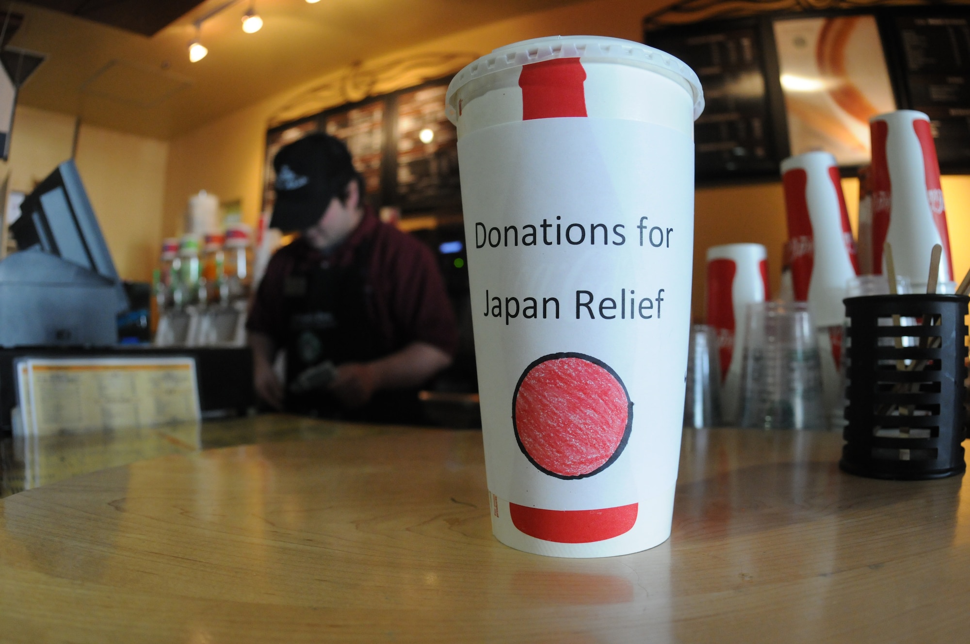 A cup displaying a representation of the Japanese sun and the words, "Donations for Japan relief" sits on the Mokuteki Cafe counter here April 5. The baristas made the unanimously decision to donate any tips made since March 11th to aid Japan and on April 5 the caf? management handed a $1,691 check to Misawa?s Red Cross station. (U.S. Air Force photo/Senior Airman Joe McFadden)