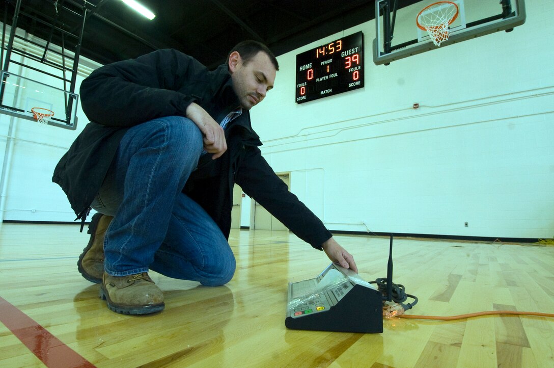 Ryan Jenkins, a contracted construction superintendent, tests the control remote on a new electronic scoreboard at the West Fitness Center April 8. The newly installed basketball court will also serve as a volleyball court for the upcoming Joint Base Andrews intramural sports season. The project is scheduled for completion by April 29. (Photo by Bobby Jones)