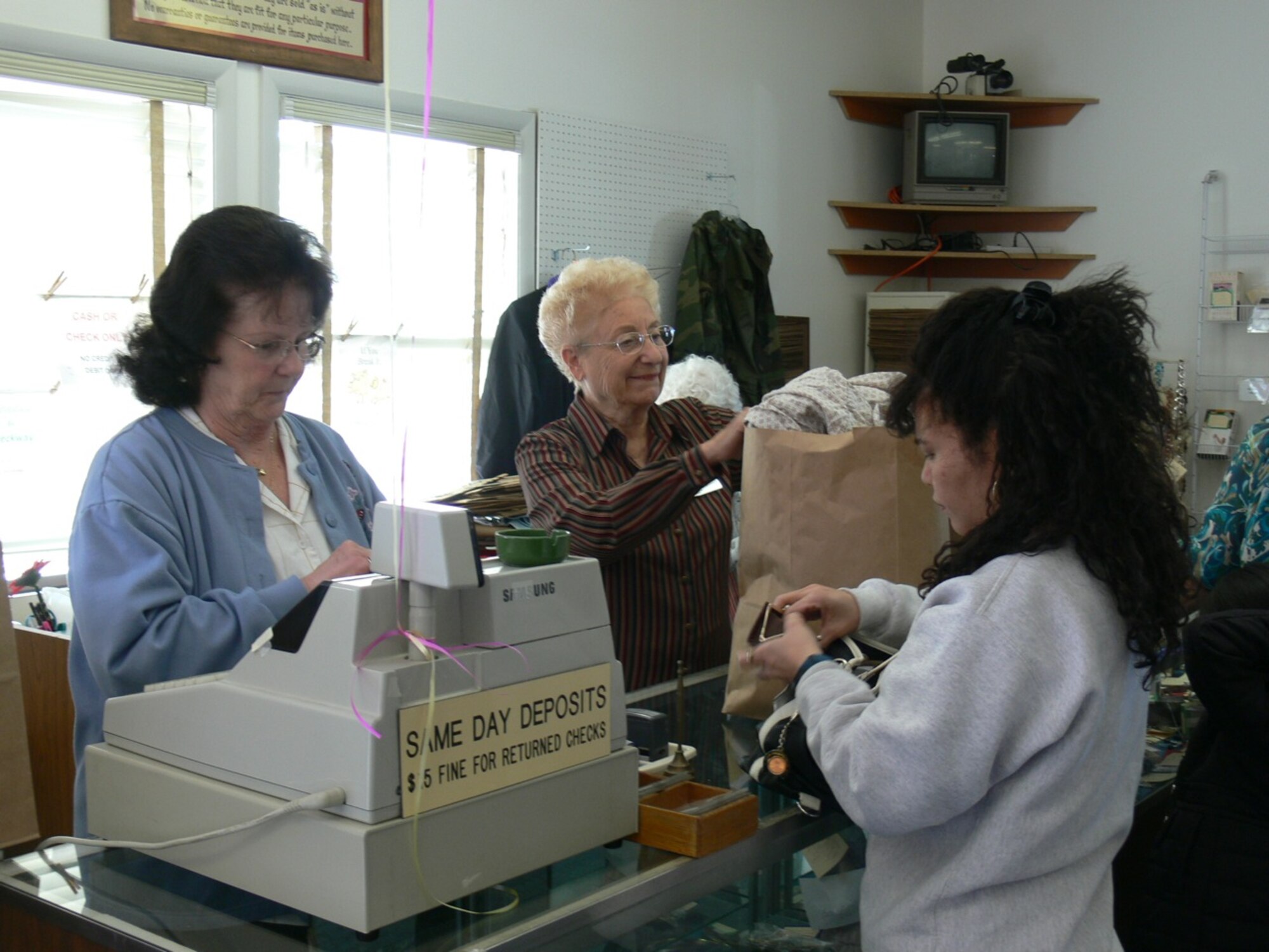 PETERSON AIR FORCE BASE, Colo. – Pat Tygard, left, and Frosso Reed, center, volunteers at the Peterson Thrift Shop, had a steady stream of customers April 5 when the shop re-opened for business. The shop had been closed for three months due to a burst water pipe. The long line at the checkout counter and the overflowing parking lot were an indication that the shop, which sells donated items and operates as a consignment store, was missed. The shop, which is owned and operated by the Peterson Spouses’ Club, had an impressive inventory for its first day back in business. Although the store had been closed, donations kept coming in those three months. The Thrift Shop, Building 615 off Otis Street and Wurtsmith Avenue, is open 9 a.m. to 2 p.m. Tuesday to Friday and 10 a.m. to noon on the first and third Saturday of the month. Hours of consignment are 9:30 to noon Tuesday to Friday. For information, call the thrift shop at 596-4463. (U.S. Air Force photo/Monica Mendoza)