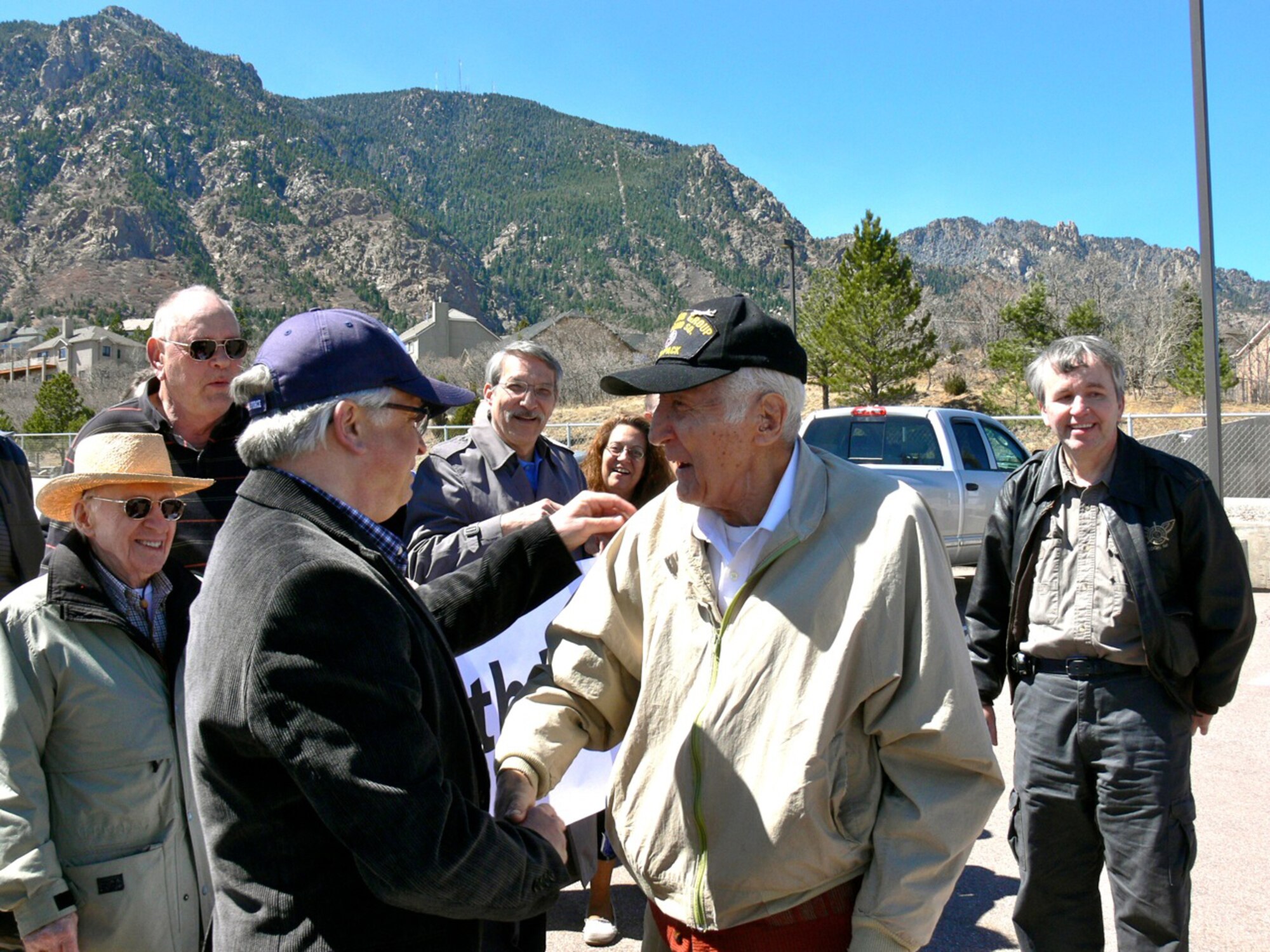 Jeff Tallman, left, greets John Mutu at the Cheyenne Mountain Air Force Station visitor’s center April 4 for a surprise 90th birthday celebration for Mr. Mutu, retired U.S. Air Force master sergeant. Twenty-two of Mr. Mutu’s former CMAFS colleagues and family members surprised him with a reunion and tour of their former workplace. Mr. Tallman was an airman first class in 1975 when Mr. Mutu, a World War II veteran working as a Department of Defense civilian on CMAFS, took him under his wing in the communication squadron’s computer maintenance department. Mr. Mutu and his former colleagues worked on CMAFS during the 1970s. (U.S. Air Force photo/Monica Mendoza)  