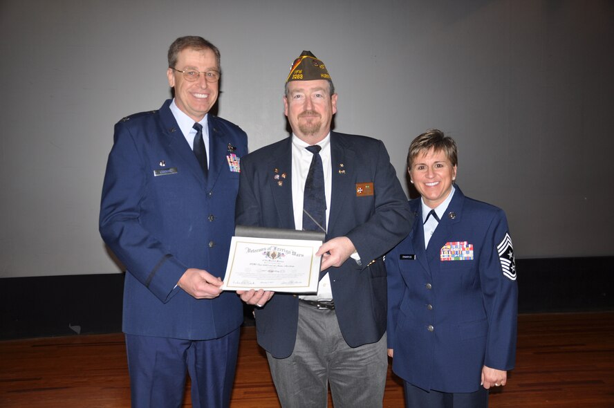 WRIGHT-PATTERSON AIR FORCE BASE, Ohio - Mr. Gerald Constable, Veterans of Foreign War Post 3283 commander, presents Col. Stephen Goeman, 445th Airlift Wing commander, an adopt-a-unit program certificate, as Chief Master Sgt. Peri Rogowski, 445th AW command chief, looks on during the April 3 commander’s call. The VFW Post 3283, based out of Huber Heights, Ohio, and its Ladies Auxiliary adopted the 445th AW Jan. 5. The certificate along with assistance and support is given to the officers, noncommissioned officers, and enlisted men and women of the wing, “to show the concern, gratitude and admiration felt for those serving this great nation.” (U.S. Air Force photo/Senior Airman Shenchia Chu)