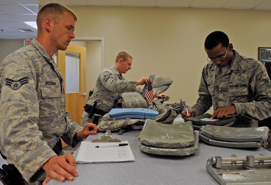 Airman 1st Class Cameron Curry (right), 2nd Logistics Readiness Squadron mobility apprentice, assists Senior Airman Bryan Dickerson and Airman 1st Class Joshua Cooper, 2nd Security Forces Squadron, with deployment and training gear on Barksdale Air Force Base, La., April 12.  The 2 LRS individual protective equipment section issues and inspects deployment and training gear including gas masks, inner ballistic armor, chemical warfare gear and weapons. (U.S. Air Force photo/Staff Sgt. John Gordinier)