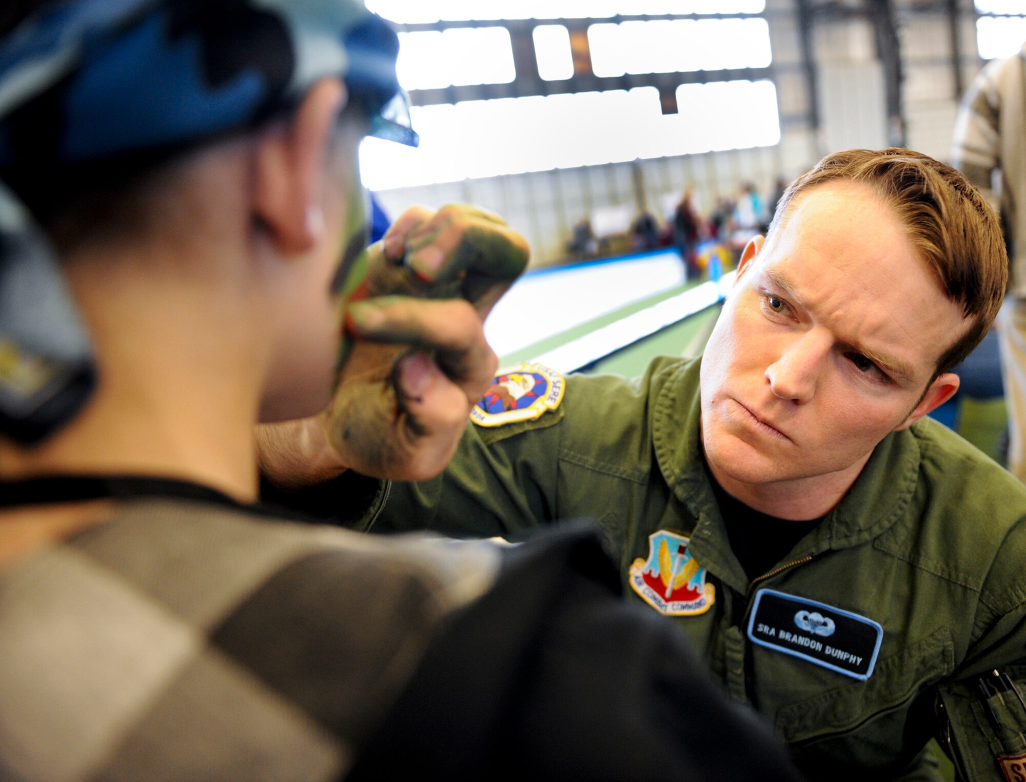 Senior Airman Brandon Dunphy, 28th Operations Support Squadron survival, evasion, resistance and escape NCO in charge, paints the faces of children during “KUDOS, SUDOS and TUDOS,” April 09, 2011, at Ellsworth Air Force Base. The event stands for kids, teachers and spouses understanding the Deployment Operations and provides each a better understanding of deployments.  (U.S. Air Force photo/Senior Airman Adam Grant)  