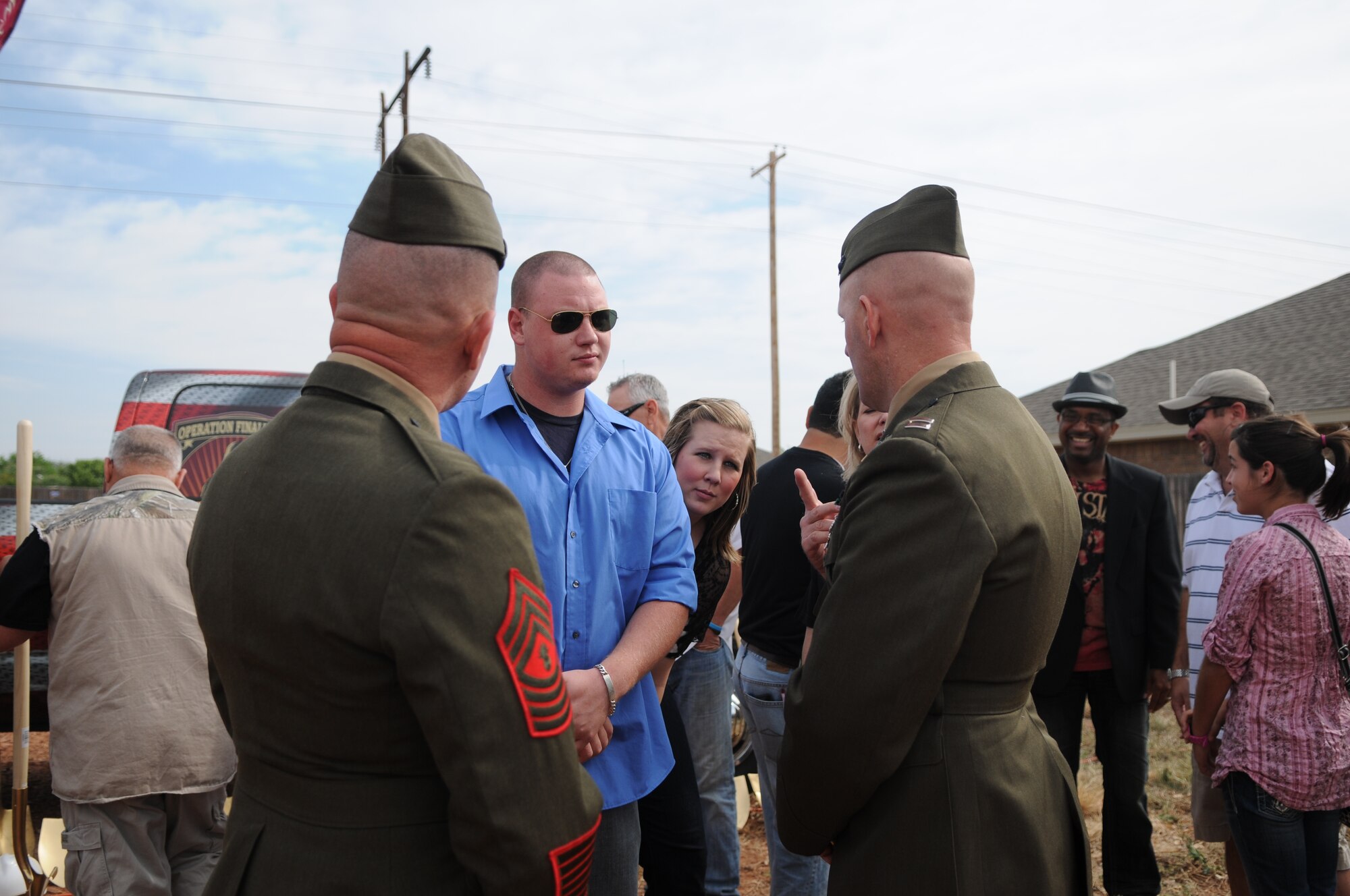 Marine Capt. Douglas March, Marine Corps Detachment Commanding Officer and Marine Master Gunnery Sgt. Peter Bordeleau, MCD Senior Enlisted Advisor chat with Retired Lance Cpl. Samuel Marley as his wife Jaci looks on during the Operation FINALLY HOME groundbreaking ceremony, April 9. (U.S. Air Force photo/Staff Sgt. Heather Rodgers)