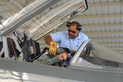 Prince Valair, 12th Flying Training Wing maintenance directorate, straps in Lt. Col. Rich Flake, 560th Flying Training Squadron, prior to a T-38 Talon launch. Maintenance workers at Randolph prepare and launch a large variety of aircraft daily.(U.S. Air Force photo/Rich McFadden)