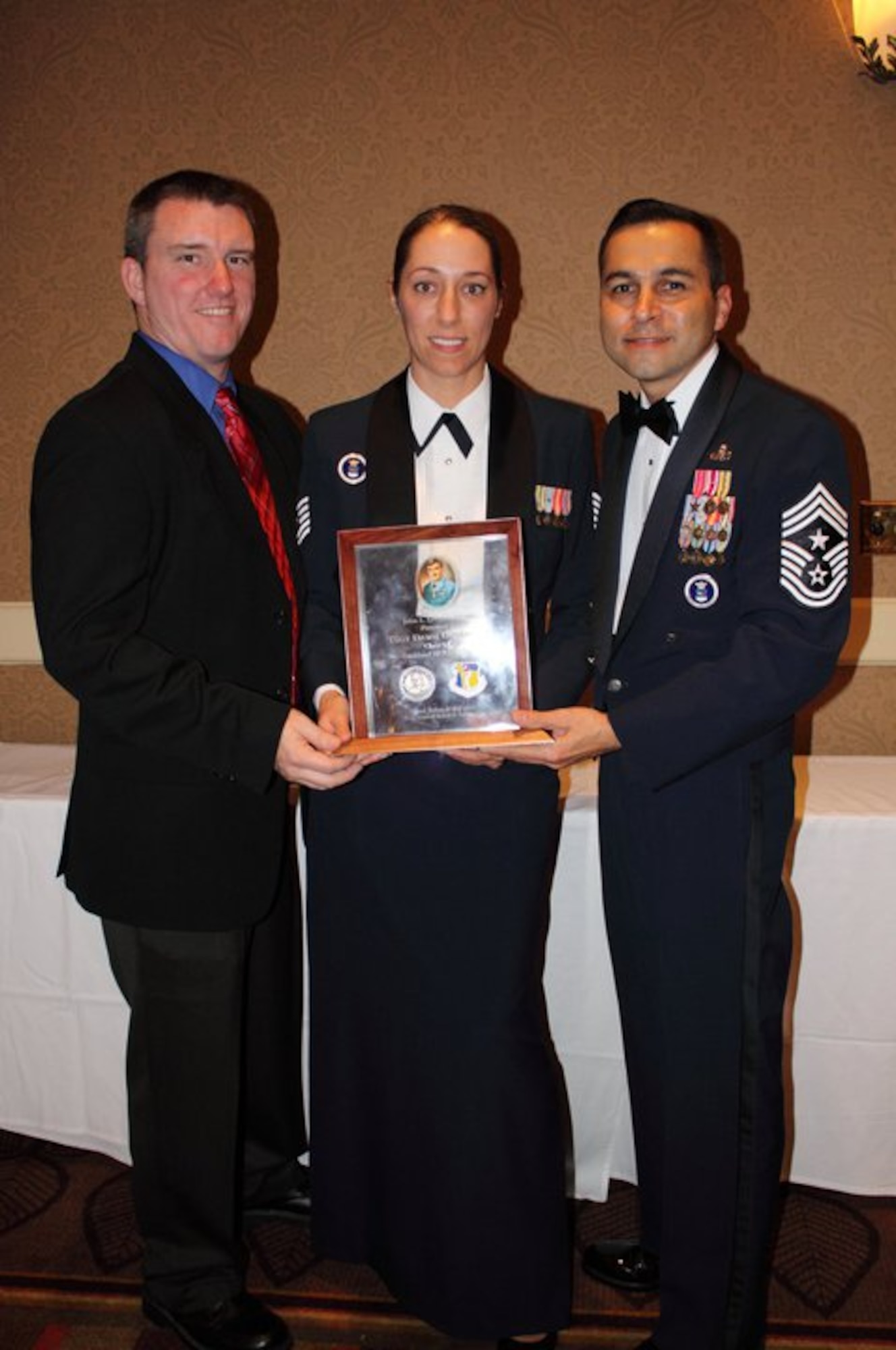 (l-r) Robert Dominguez, Tech. Sgt. Dawn Dominquez, Chief Master Sgt. Ruben Gonzalez. Tech. Sgt. Dawn Dominguez, 341st Recruiting Squadron recruiter, receives the John Levitow award presented by Chief Master Sgt. Ruben Gonzalez, Air Force Recruiting Service command chief, at Lackland Air Force Base Non-Commissioned Officer Academy graduation ceremony.(USAF/Courtesy photo) 
