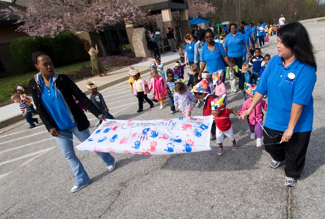 Kim Jennifer, Child Development Center II program assistant, left, and Remy Wilkins, CDC II lead program assistant, lead approximately 215 CDC II children during an annual parade march in observance of Month of the Military Child April 11. (Photo by Bobby Jones) 