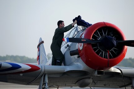 A Charleston Air Expo 2011 volunteer removes the cover off of one of the GEICO Skytypers' SNJ-2 aircraft before their performance on April 9 at Joint Base Charleston, S.C.  GEICO skytypers performed low-level precision formation flying for nearly 80,000 people during the Charleston Air Expo 2011.  (U.S. Air Force photo/ Staff Sgt. Nicole Mickle)