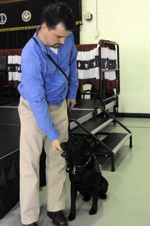 Retired Marine Sgt. Jason Blondin, from Wounded Warrior Battalion East, gives a treat to his newly adopted four-year-old black Labrador Retriever, Eden, which was provided by Carolina Canines for Service and the Naval Consolidated Brig Charleston during a ceremony at NAVCONBRIG, March 31.  The partnership of CCFS and NAVCONBRIG provides highly trained service dogs to wounded warriors.  (U.S. Navy photo/Machinist’s Mate 3rd Class Brannon Deugan)