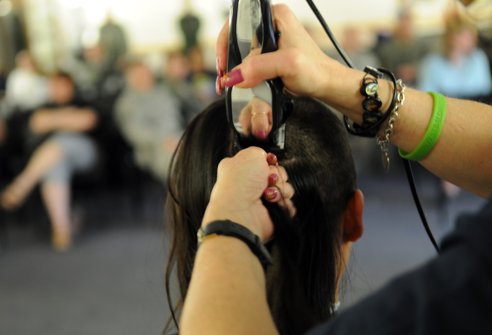 RAF MILDENHALL, England -- Jeanette Jackson, a barber from the Flightline Barbershop here, removes a chunk of Margaret Albaugh’s, wife of Capt. Clinton Albaugh, 100th Air Refueling Wing plans and programs, hair during a St. Baldrick’s Foundation event at the 100th Operations Group auditorium April 7, 2011. According to the St. Baldrick’s Foundation website, the foundation is a volunteer-driven charity committed to funding research to find cures for childhood cancers. Volunteers for the organization raise funds by taking pledges to shave off their hair. Along with the pledges, Mrs. Albaugh donated her hair to Locks of Love. The Century Tanker Committee and spouses raised more than $7,500 for the foundation. (U.S. Air Force photo/Airman 1st Class Rachel Waller)