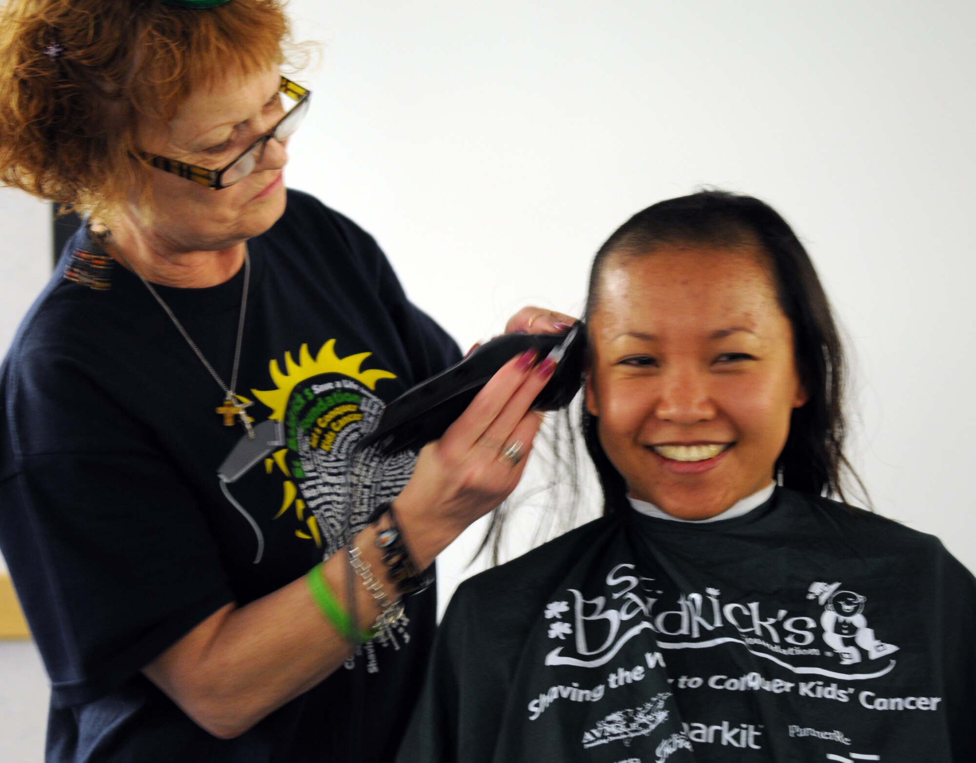 RAF MILDENHALL, England -- Jeanette Jackson, a barber from the Flightline Barbershop here, shaves off Margaret Albaugh’s, wife of Capt. Clinton Albaugh, 100th Air Refueling Wing plans and programs, hair during a St. Baldrick’s Foundation event at the 100th Operations Group auditorium April 7, 2011. According to the St. Baldrick’s Foundation website, the foundation is a volunteer-driven charity committed to funding research to find cures for childhood cancers. Volunteers for the organization raise funds by taking pledges to shave off their hair. Along with the pledges, Mrs. Albaugh donated her hair to Locks of Love. The Century Tanker Committee and spouses raised more than $7,500 for the foundation. (U.S. Air Force photo/Airman 1st Class Rachel Waller)
