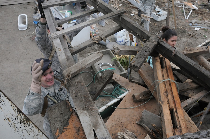 HACHINOHE, Japan --  Master Sgt. Donald Kuehl, 35th Security Forces Squadron, loads debris into the back of a flatbed truck with the help of other Misawa residents during a relief operation to Hachinohe April 7. Misawa Helps, a Misawa Air base-sponsored agency coordinating relief efforts, has organized more than 30 volunteer opportunities involving more than 1400 base residents since March 11. (U.S. Air Force photo/Staff Sgt. Erica Picariello)
