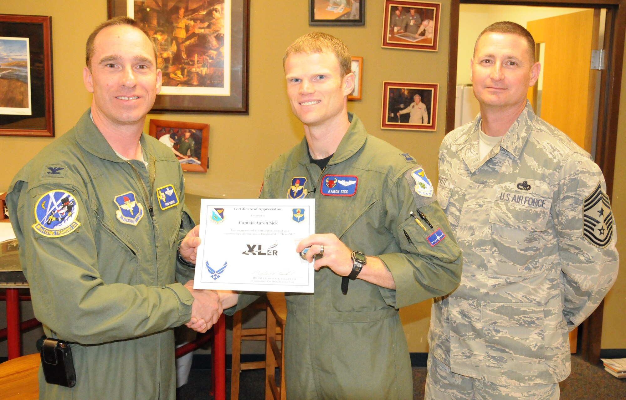 LAUGHLIN AIR FORCE BASE, Texas – Captain Aaron Sick, 87th Flying Training Squadron instructor pilot, poses with Col. Thomas Murphy, 47th Flying Training Wing vice commander, and Chief Master Sgt. Ray DeVite, 47th FTW command chief, after being presented the XLer of the Week award here April 6. The XLer is a weekly award chosen by wing leadership and given to those who consistently make outstanding contributions to Laughlin and their unit. (U.S. Air Force photo by Airman 1st Class Blake Mize)
