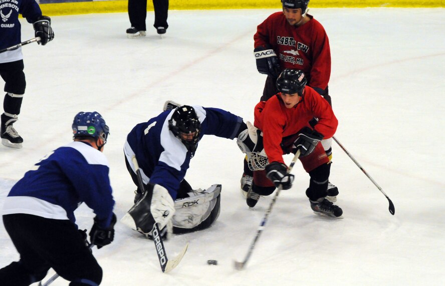 A hockey player from the 148th Fighter Wing, Duluth, Minn. (red uniform) tries to stick handle around the goaltender for the 133rd Airlift Wing, St. Paul, Minn. during the 2011 Minnesota National Guard hockey tournament.  The tournament was held at the Duluth Heritage Sports Center in Duluth, Minn.  (U.S. Air Force photo by Master Sgt. Ralph J. Kapustka)