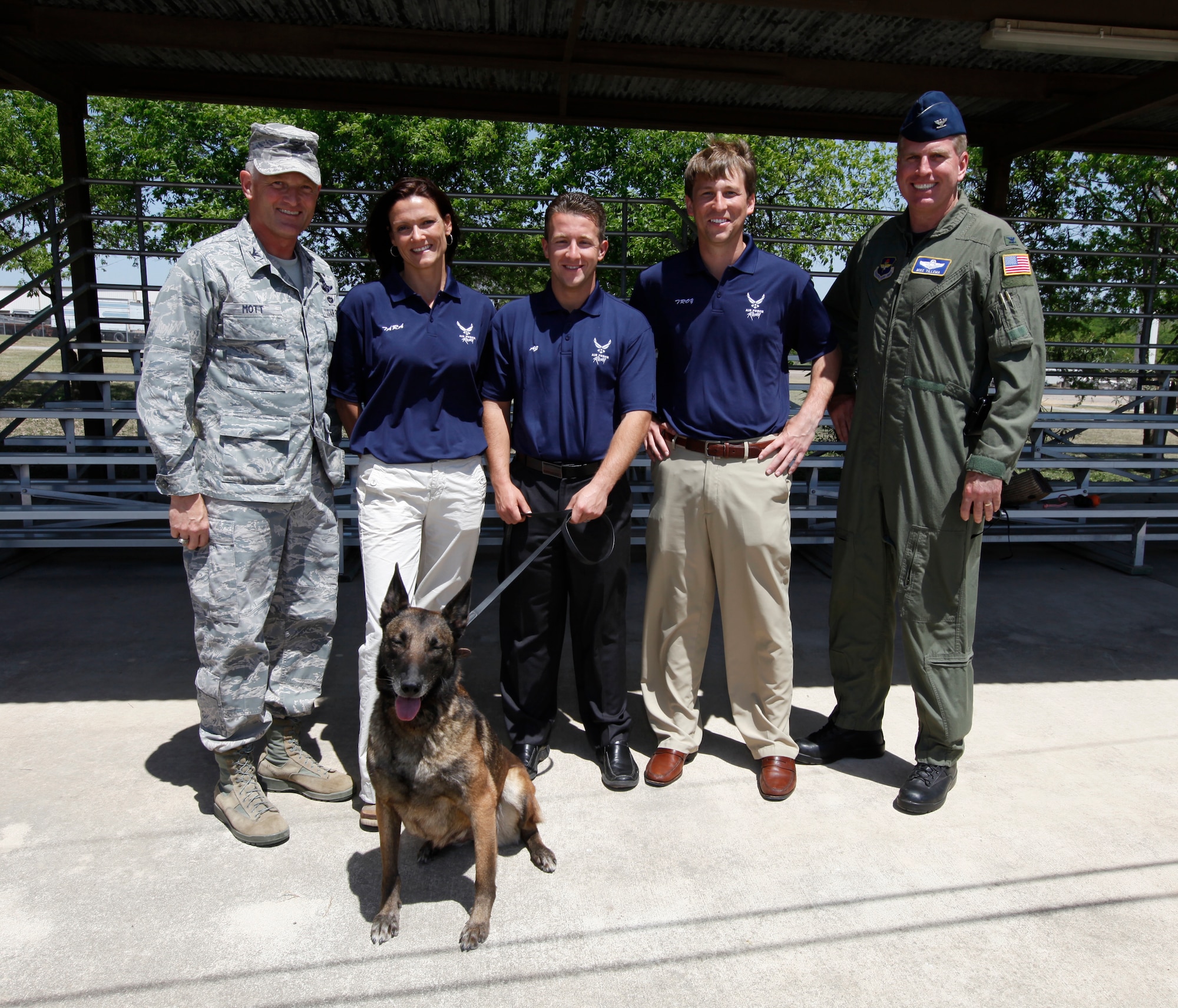 (l-r) Col. William Mott, 37th Training Wing commander; Tara Ragan, Walldinger Racing vice president; A.J. Allmendinger, , NASCAR driver for the Air Force-sponsored #43 car; Troy Yarborough, Richard Petty Motor Sports car #43 account manager; and Col. Mike Tillema, Air Force Recruiting Service strategic marketing and communication chief, pose with Ffayd, a Belgium Malinois working dog. Ffayd demonstrated her ability to neutralize a threat during the AFRS “Dip into the Blue” tour at the 341st TRS Military Working Dog School at Lackland Air Force Base, Texas April 6. (Air Force photo/Tech. Sgt. Jeffrey Wolfe)