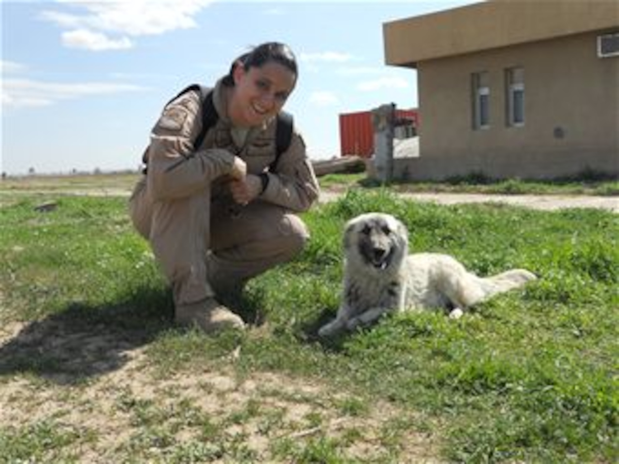 KIRKUK REGIONAL AIR BASE, Iraq -- Capt. Kirsten Ellis, 521st Air Expeditionary Advisory Squadron T1 instructor pilot, visits with Fatoon April 5. The dog and her seven pups were found on the flight line area of the base. Captain Ellis has liaised with Operation Baghdad Pups in an effort to save them from certain destruction. Captain Ellis is deployed from Laughlin and is a native of Atlanta, Ga. (Courtesy photo) 

