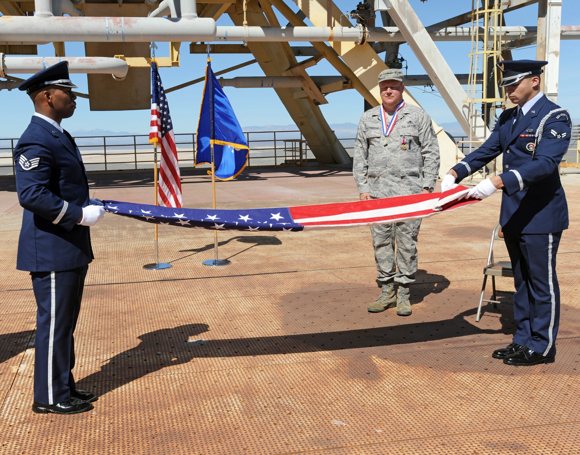 Senior Master Sgt. Jeff R. Buetemeister, Air Force Research Laboratory Senior Logistics manager and Quality Assurance superintendent, watches as his retirement flag is folded during a retirement ceremony at Test Stand 1-C March 31. Since arriving at AFRL, Sergeant Buetemeister has been responsible for revitalizing and standardizing the logistics program and taking it from “Non-Compliant” during the 2008 AFRL Staff Assistance Visit to a near flawless program that earned an overall “Excellent” during the 2011 Air Force Material Command, Logistics Compliance Assessment Program Inspection. Sergeant Buetemeister retired after 22 years in the Air Force. (Air Force photo by Ray Dyakon)