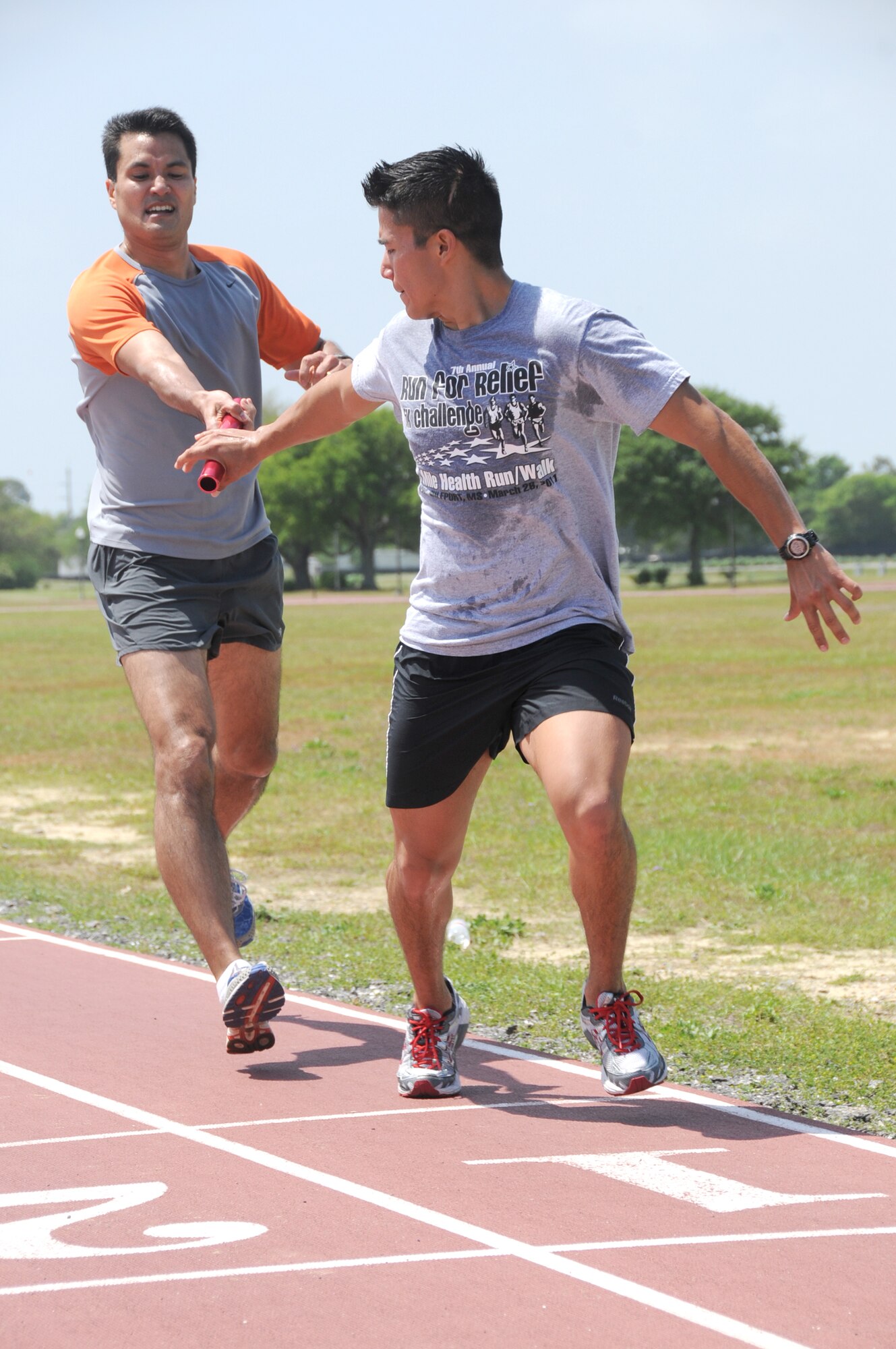 Sasaki, left, passes the baton to Balderas after completing a relay lap at the Triangle Track.  (U.S. Air Force photo by Kemberly Groue)