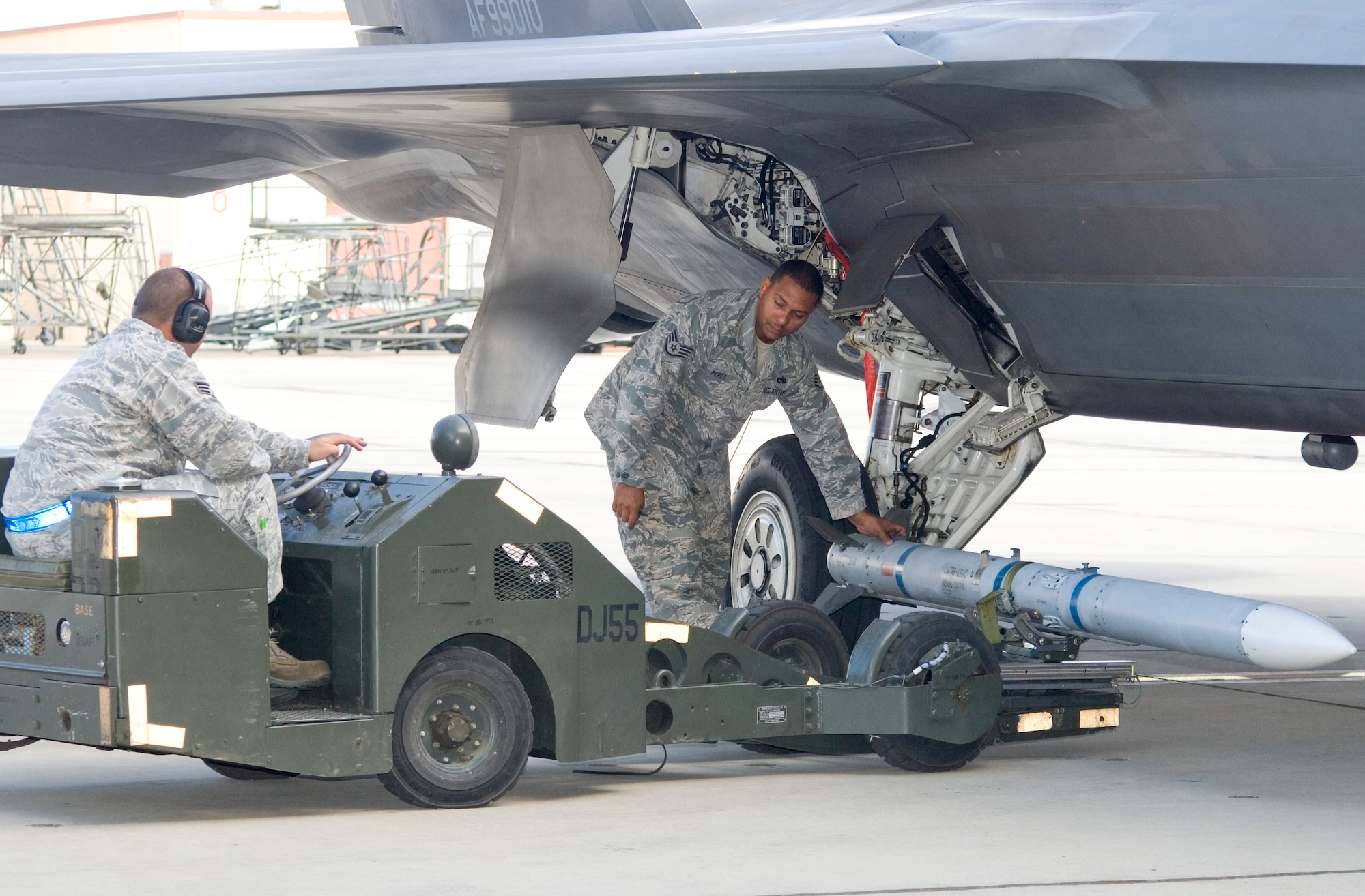 Senior Airman Douglas Covey delivers a CATM-120 AMRAAM missile to be loaded onto an F-22 Raptor while team leader Staff Sgt. Alexe Perez supervises. The R-3 team from the 411th Aircraft Maintenance Unit won this quarter's Load Crew Competition. The F-22 loaders edged out the JSF-1 crew competing for the 461st Aircraft Maintenance Unit. (Air Force photo by Edward Cannon)
