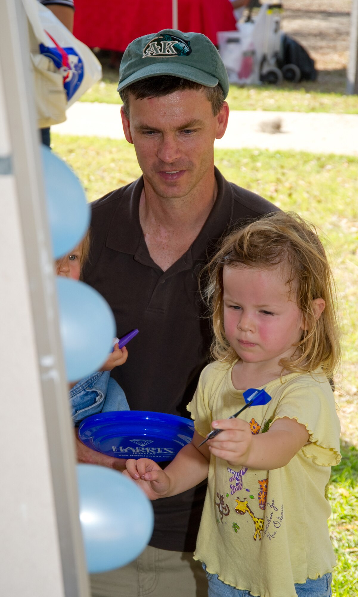Three-year-old Ashley Nelson and her dad, Tim, play a balloon-popping game at Saturday's Child Pride Day celebration at marina park.  Ashley's mom is Maj. Rachel Nelson, 81st Medical Operations Squadron.  (U.S. Air Force photo by Adam Bond)
