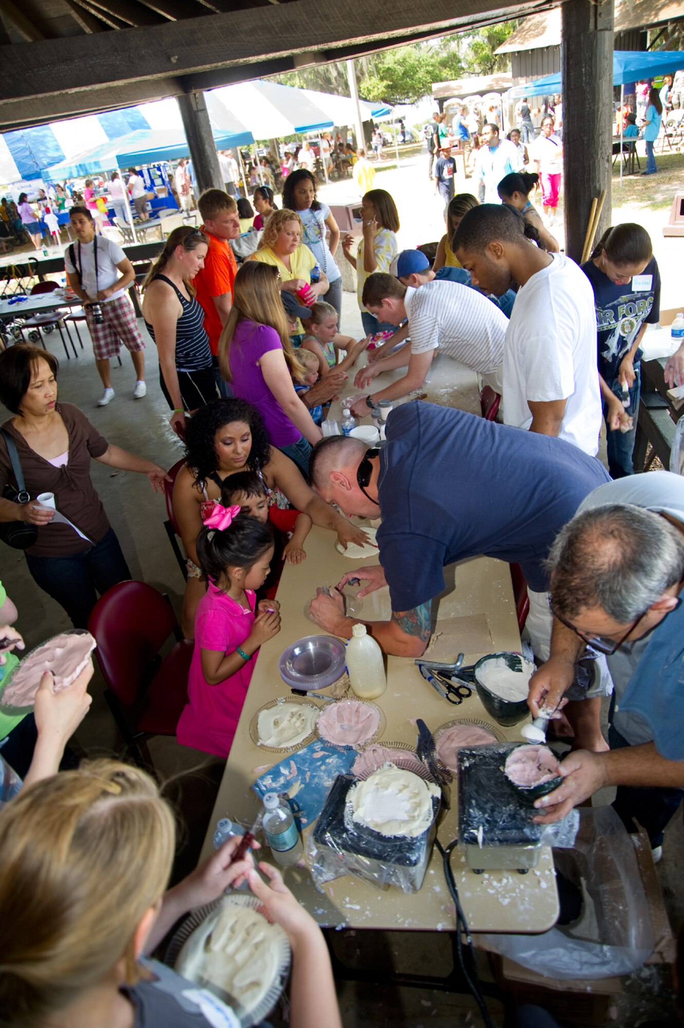 Parents and children gather at marina park to make hand impressions in plaster. Volunteers were present to help mix, pour and set the plaster molds that would capture forever the size of the children’s hands that day.  (U.S. Air Force photo by Adam Bond)