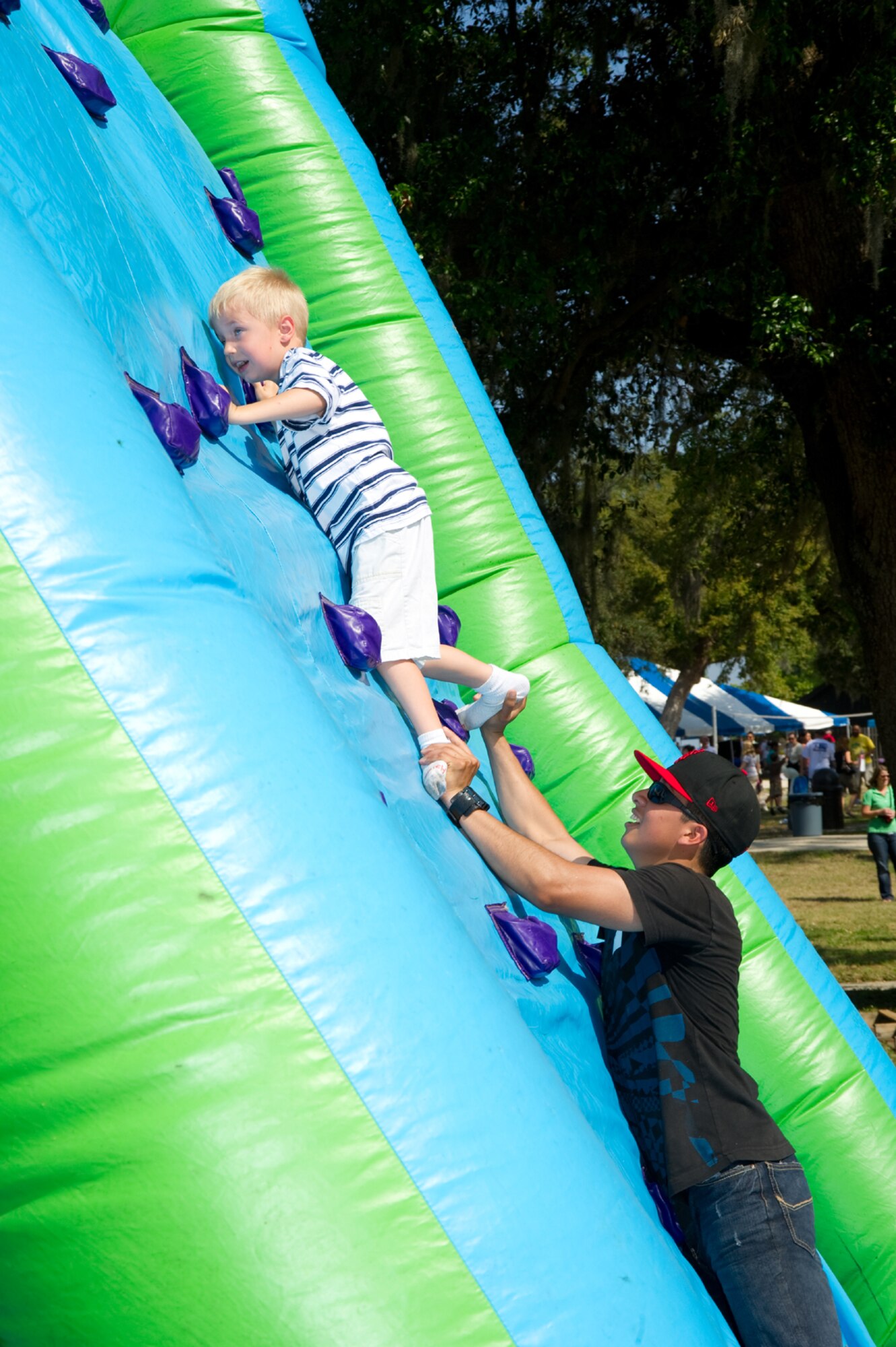 With a little help from Airman 1st Class John Rojas, 336th Training Squadron, Bryson Bingaman, 5, scales the heights of the bouncy mountain. Bryson is the son of Maj. Rich and Wanda Bingaman, 333rd TRS.  (U.S. Air Force photo by Adam Bond)