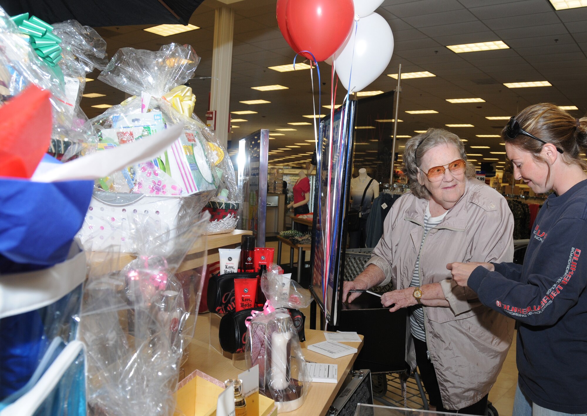 Ruth Dern of Biloxi, left, and Army Sgt. Tanya Salva sign up to win a display of prizes in celebration of the main exchange’s first anniversary in its new location, April 6. Mrs.
Dern’s husband, Paul, is a retired senior master sergeant. Sergeant Salva is assigned to the Gulfport Combat Readiness Training Center.  (U.S. Air Force photo by Kemberly Groue)