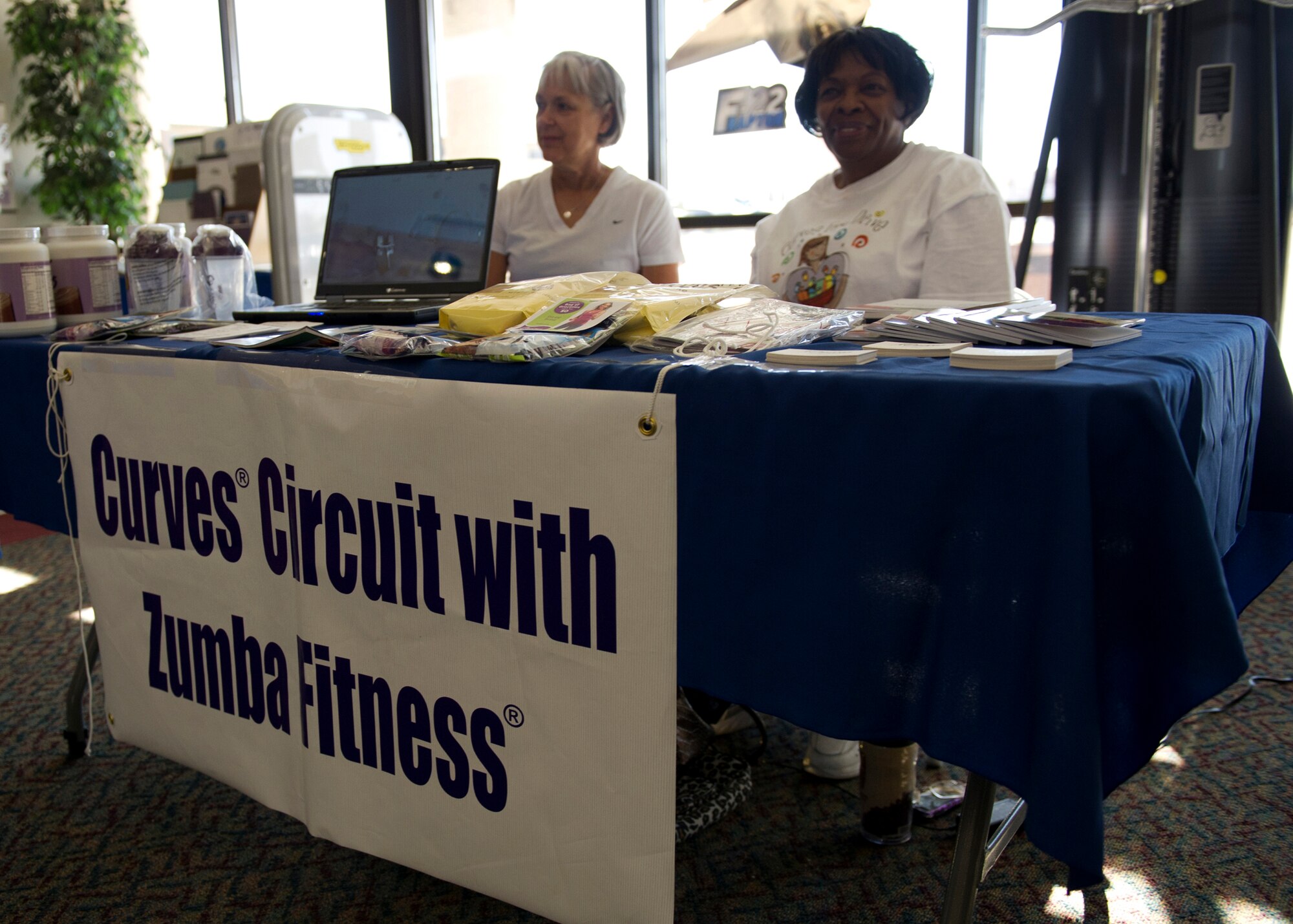 HOLLOMAN AIR FORCE BASE, N.M. -- Sue Burns, an instructor at the Alamogordo Curves Fitness Center, and owner Gertrude Proctor, advertise for their business in support of the Health And Wellness Center Open House and Joint Fitness Fair at the Domenici Fitness and Sports Center April 8, 2011. Among other classes taught at the base gym, Zumba® has become a popular class. The Alamogordo Curves Fitness Center offers a modified version of the class and many military members attend at the off base location. (U.S. Air Force photo by Airman 1st Class Eileen Payne/Released)