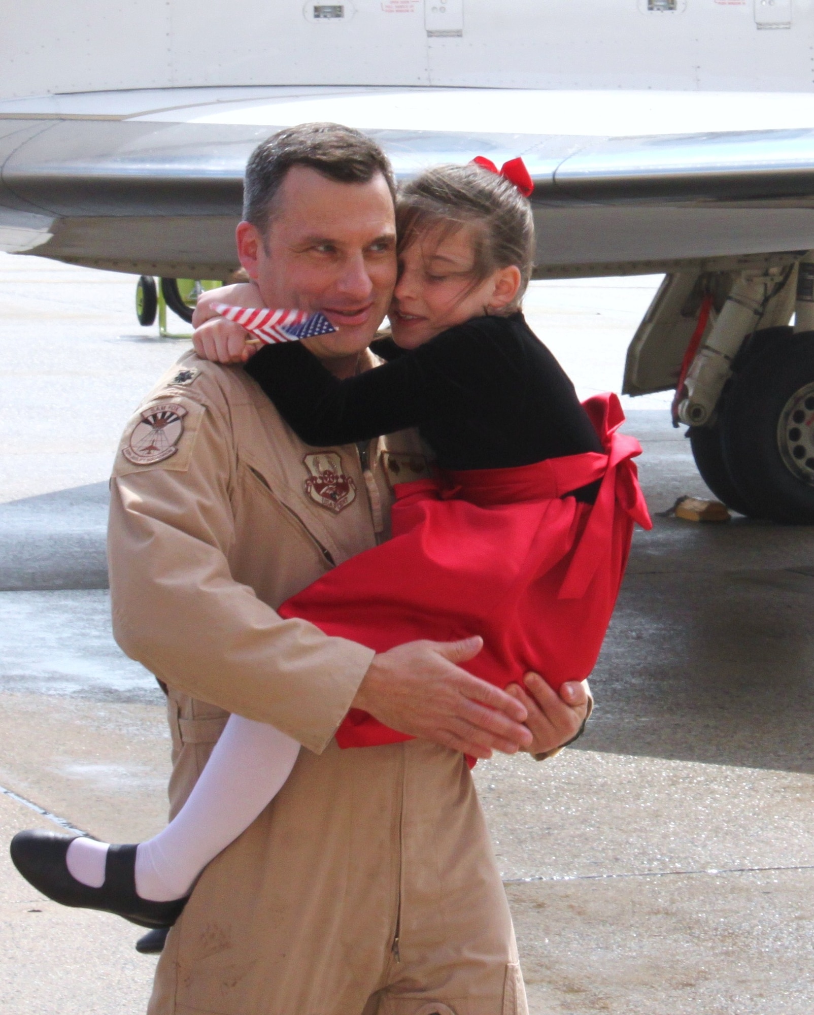 Lieutenant Colonel Jason Krinsky is embraced by his daughter Samantha upon return from his deployment as the Central Command Distinguished Visitor Flying Detachment commander. Lt. Col. Krinsky and 11 other members of the 99th Airlift Squadron were attached to the 379th Air Expeditionary Wing and flew a total of 52 Distinguished Visitor missions during their three month deployment. (U.S. Air Force photo/2nd Lieutenant Gregg Johnson)