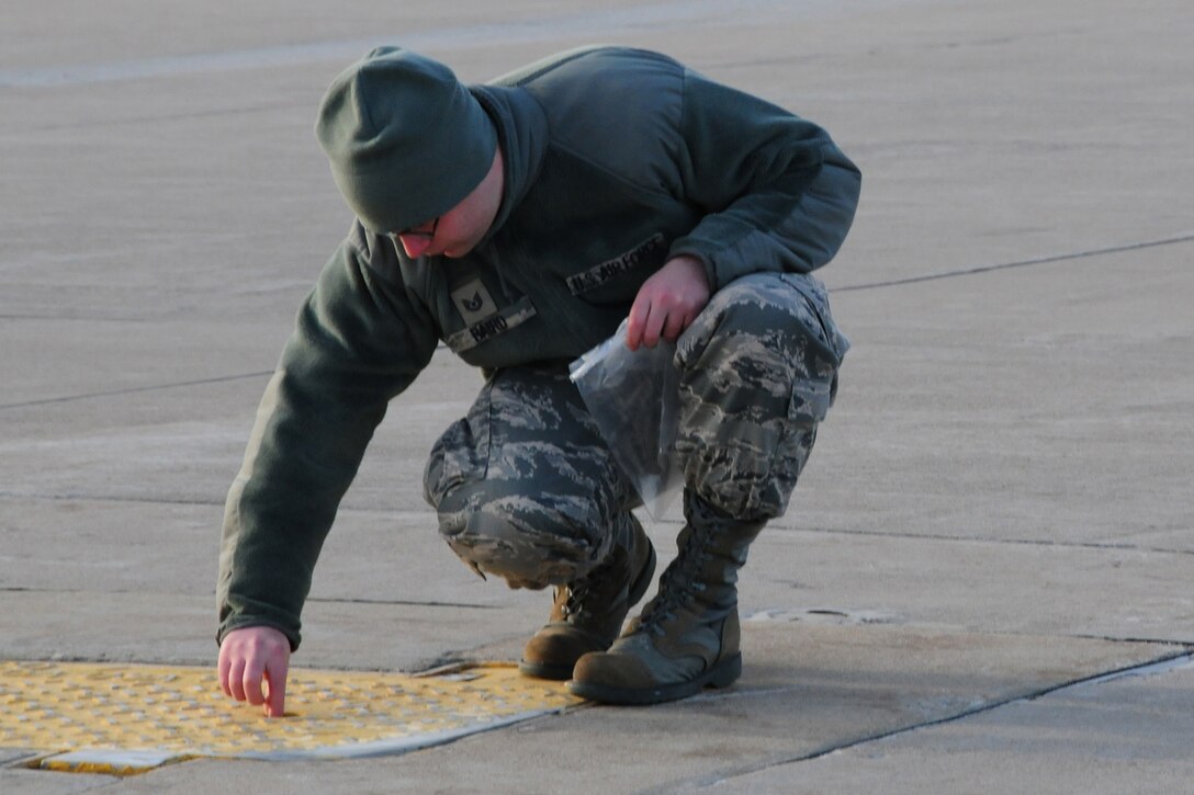 NIAGARA FALLS AIR RESERVE STATION, N.Y-  Technical Sgt. David Baird, Military Personnel Employment Specialist, 914th Airlift Wing, Niagara Falls ARS picks up a piece of Foreign Object Debris (FOD).  Typically this function is performed by maintenance and safety personnel, but it is everyone's responsibility to pick up any debris found while on the flight line.  This week many unit members volunteered to participate in this weekly activity.  (U.S. Air Force Reserve photo by Peter Borys)