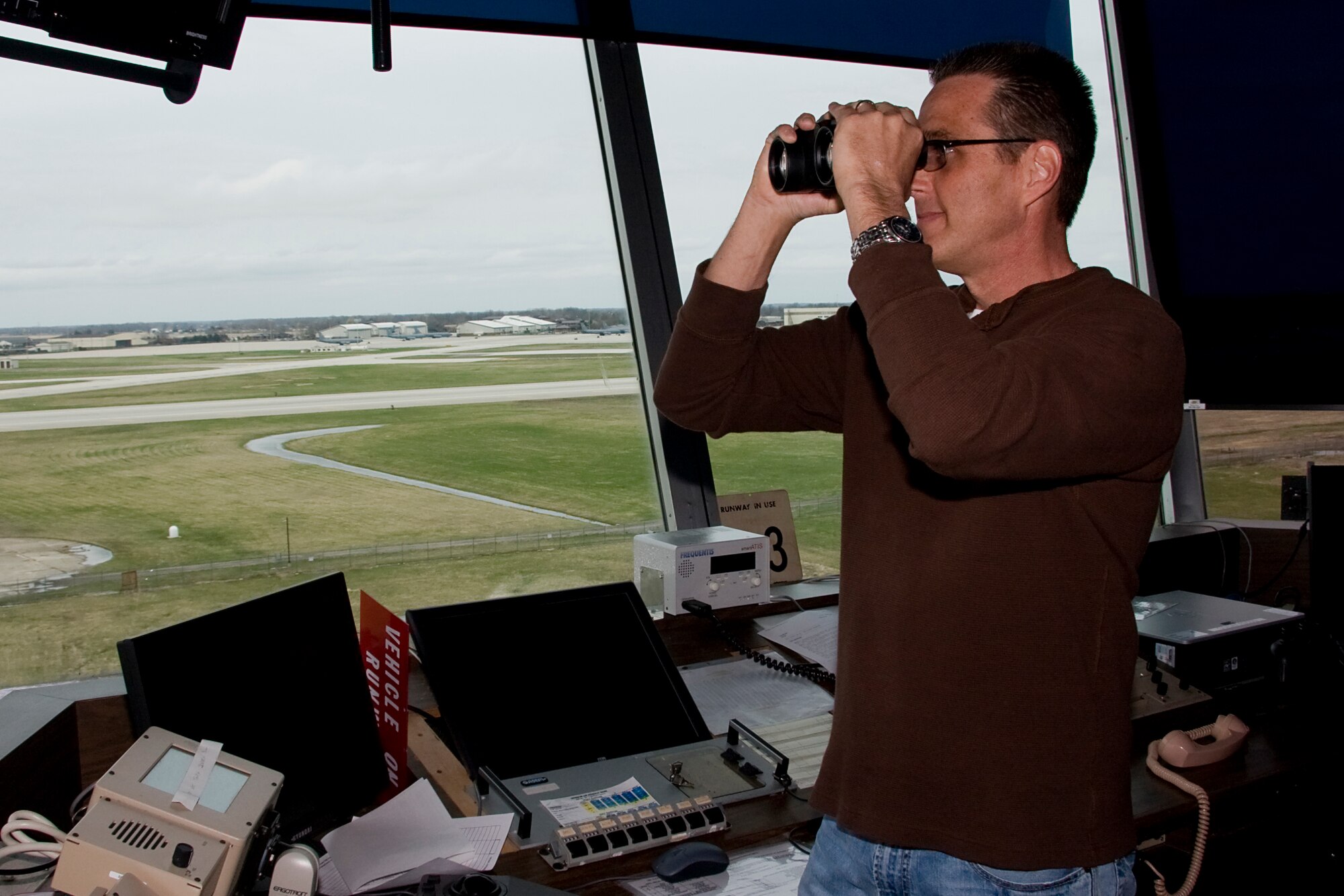 GRISSOM AIR RESERVE BASE, Ind. -- Using binoculars, Robert Moore, scans across a flight line at Grissom Air Reserve Base, Ind., April 11. Mr. Moore is a 434th Operations Support Squadron air traffic control training and standardization manager. All of Grissom's air traffic controllers are dual-qualified for both radar approach control and tower control operations. The ATC tower Mr. Moore is standing in was built in 1965 and is being replaced with a new tower that is scheduled for completion in 2012. (U.S. Air Force photo/Tech. Sgt. Mark R. W. Orders-Woempner) 
